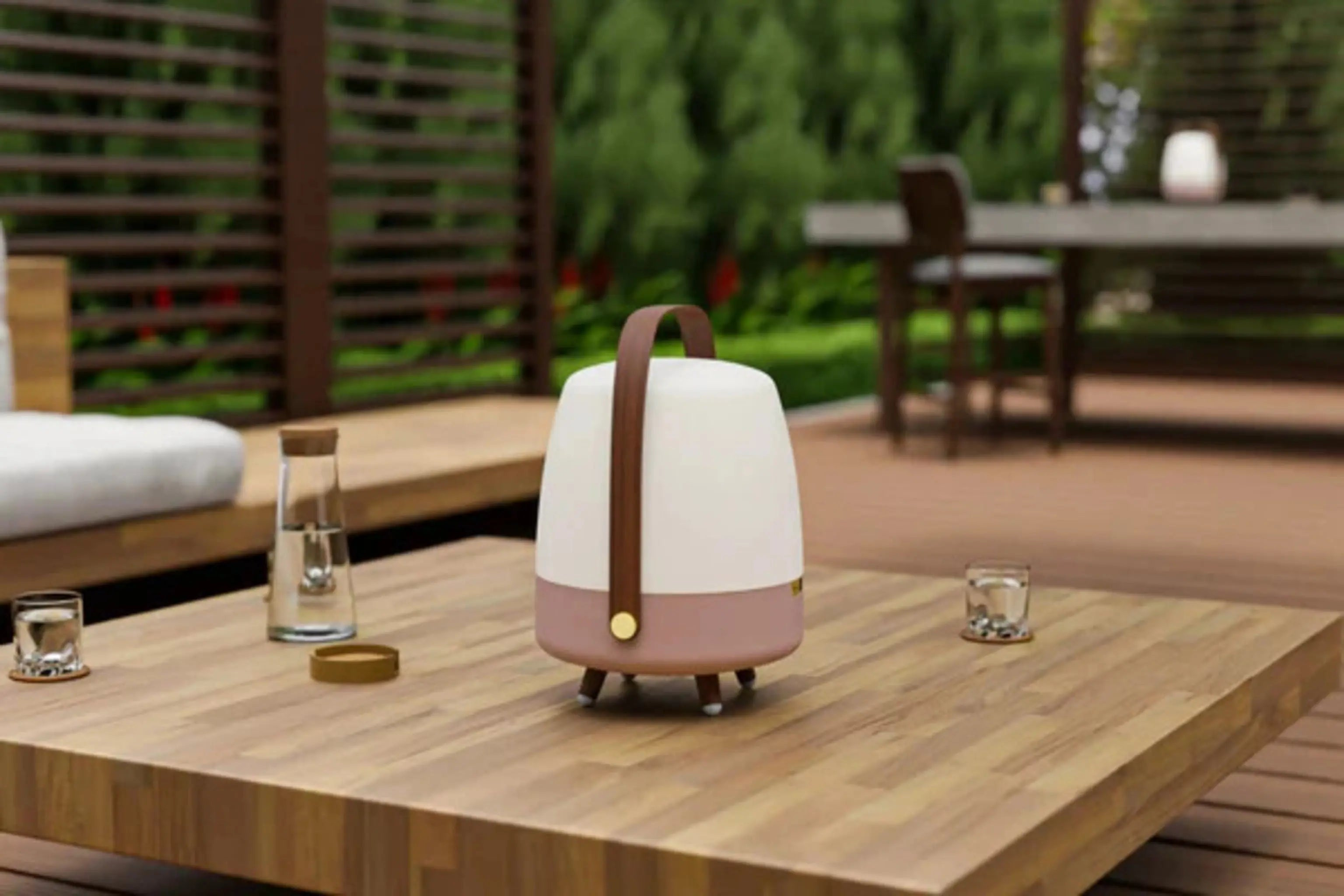 Tisch im Freien mit Lampe, Gläsern und einer Wasserflasche.