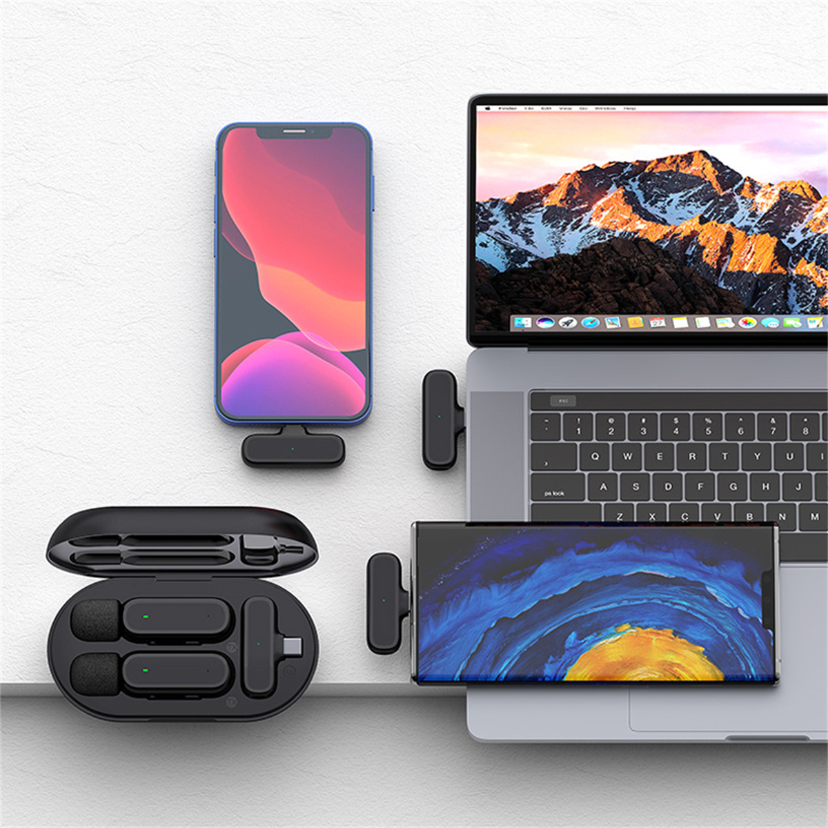 Ein Setup mit Laptop, Smartphone und drahtlosen Mikrofonen zur Audioaufnahme auf einem Schreibtisch.