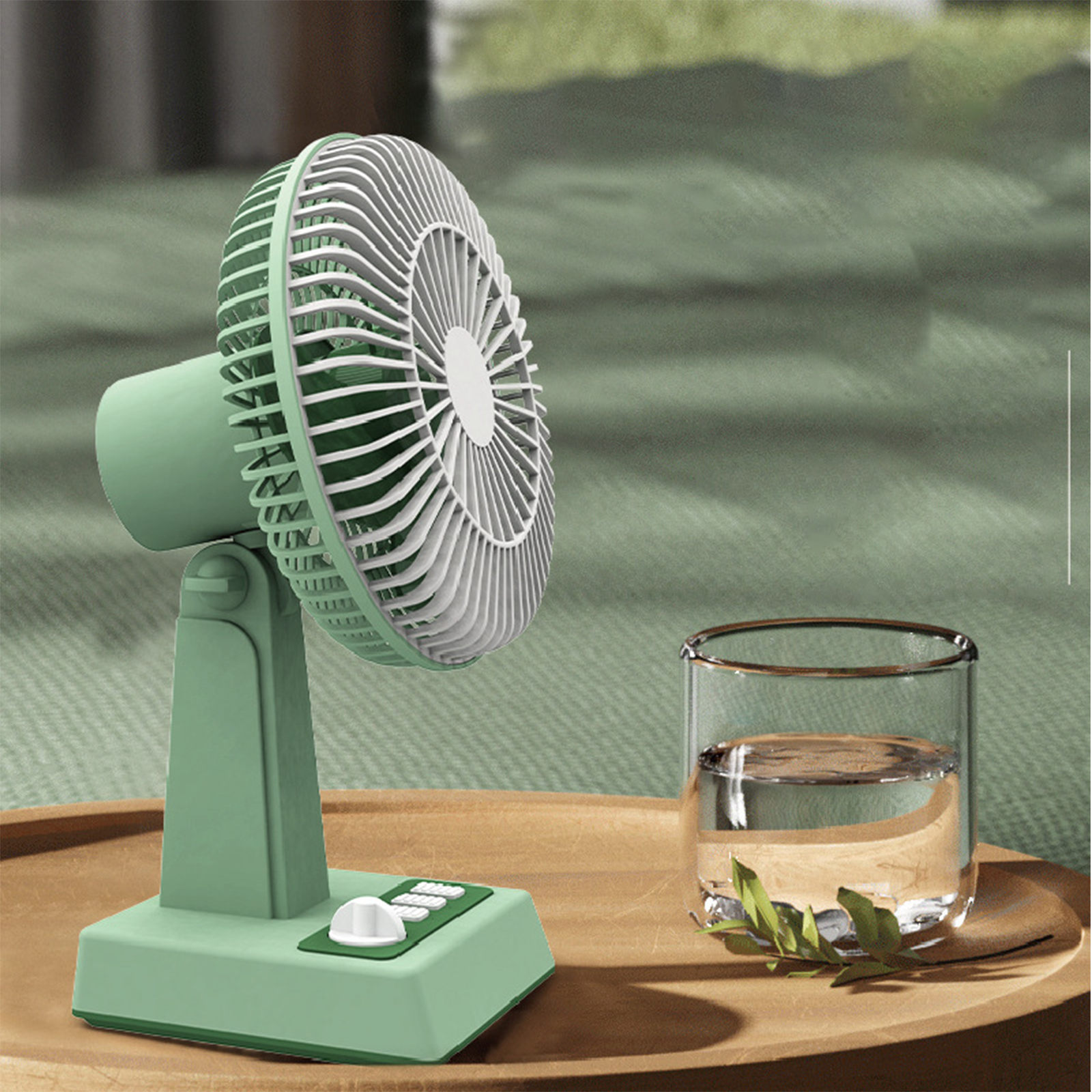 Ein kleiner, grüner, tragbarer Ventilator auf einem Holztablett mit einem Glas Wasser und einem grünen Hintergrund.