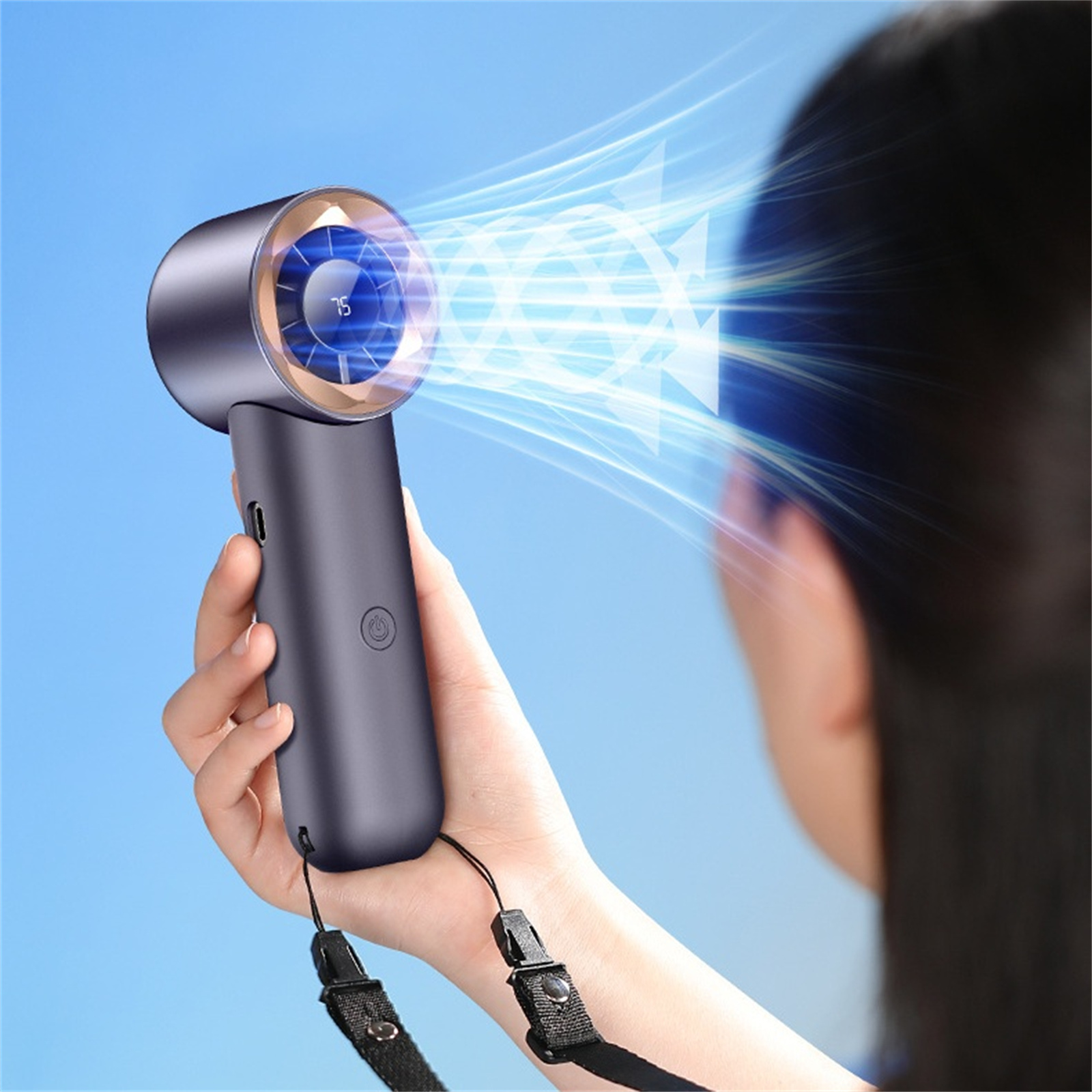 Person hält einen blauen Handventilator, blauer Himmel im Hintergrund.