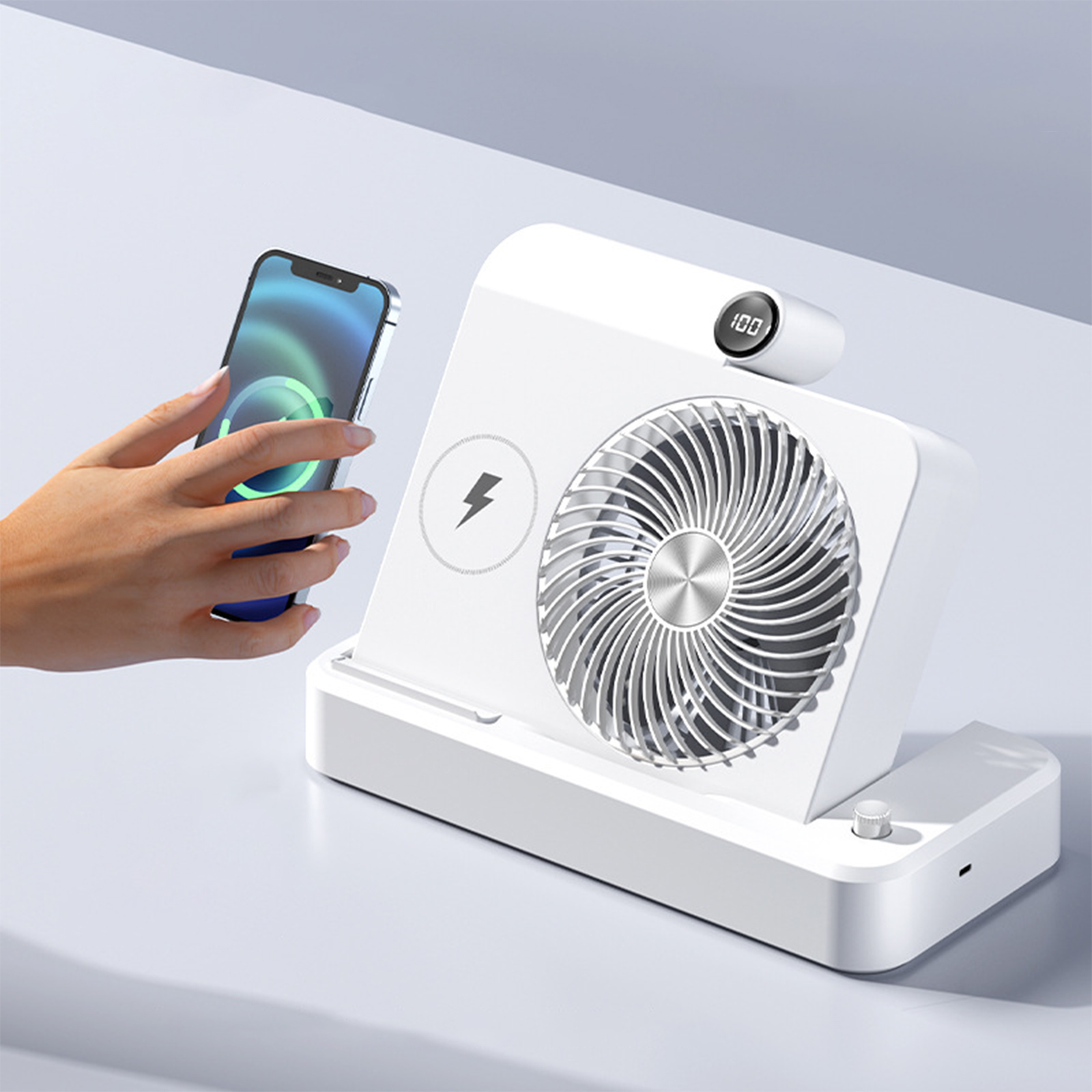 Ein weißer Ventilator mit einem ladenden Telefon. Eine Hand berührt das Telefon und zeigt volle Ladung.