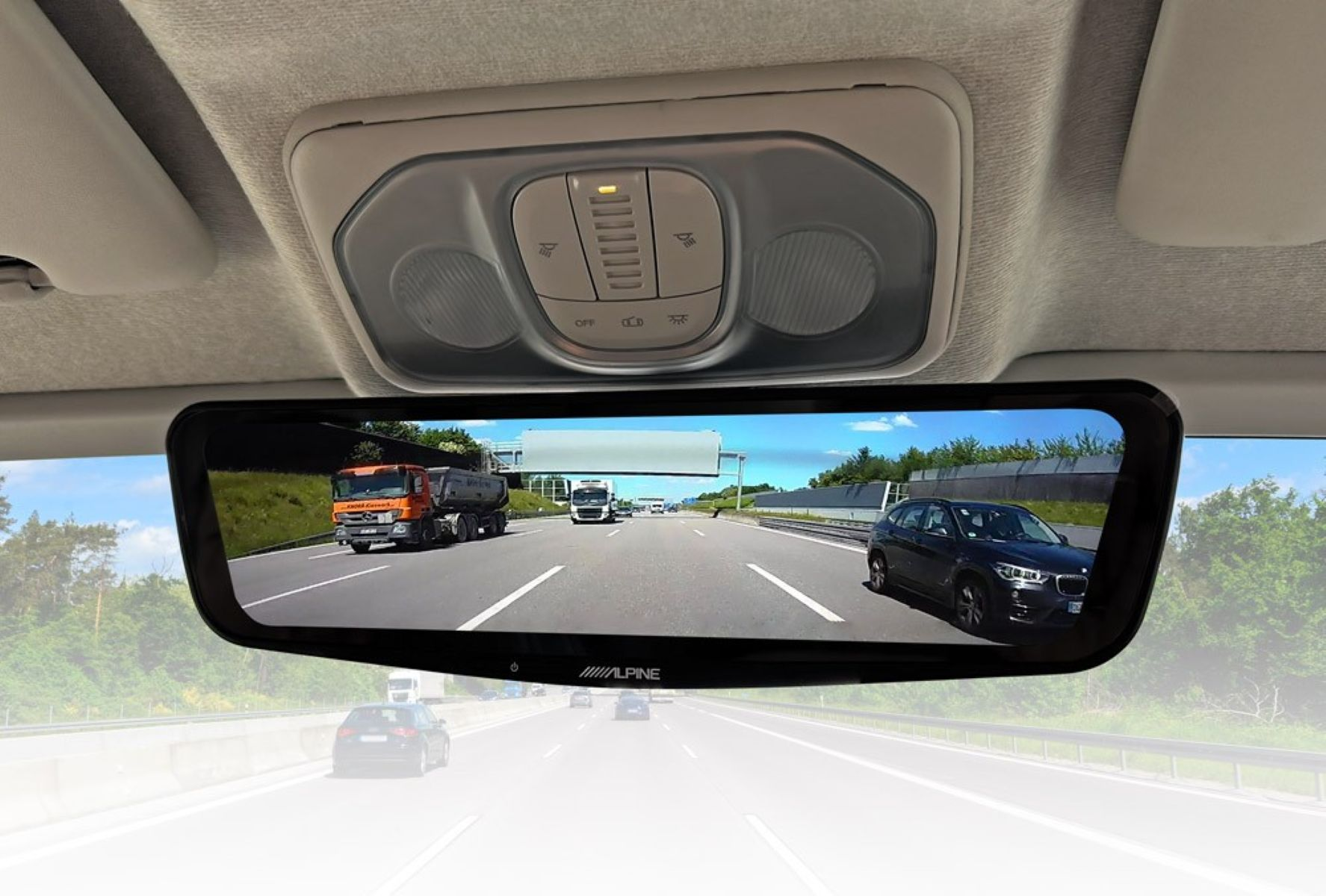 Ein Rückspiegel eines Autos, der eine Autobahnszene mit LKWs und Autos im Hintergrund zeigt.