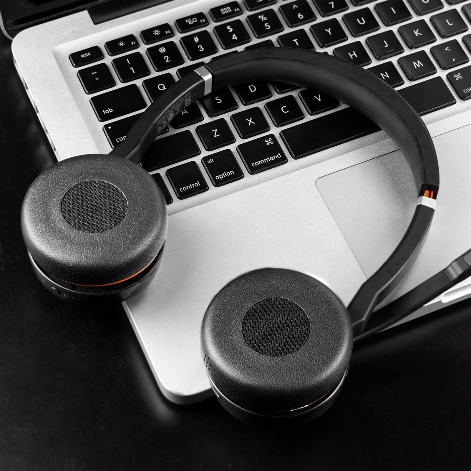 Schwarze Kopfhörer auf einer silbernen Laptop-Tastatur. Die Kopfhörer sind Over-Ear.