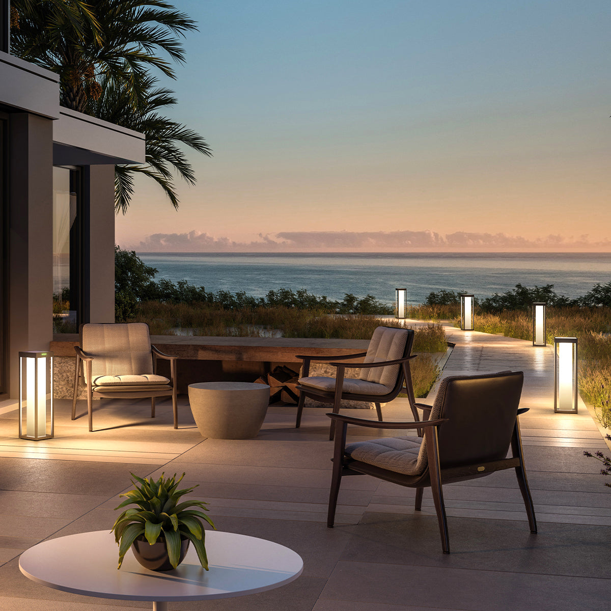 Außenbereich bei Dämmerung mit Stühlen, Tisch und Lichtern, mit Blick auf das Meer.