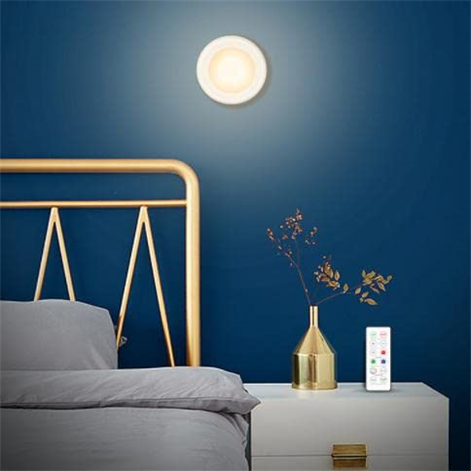 Wandleuchte mit Fernbedienung und Bett im Hintergrund.