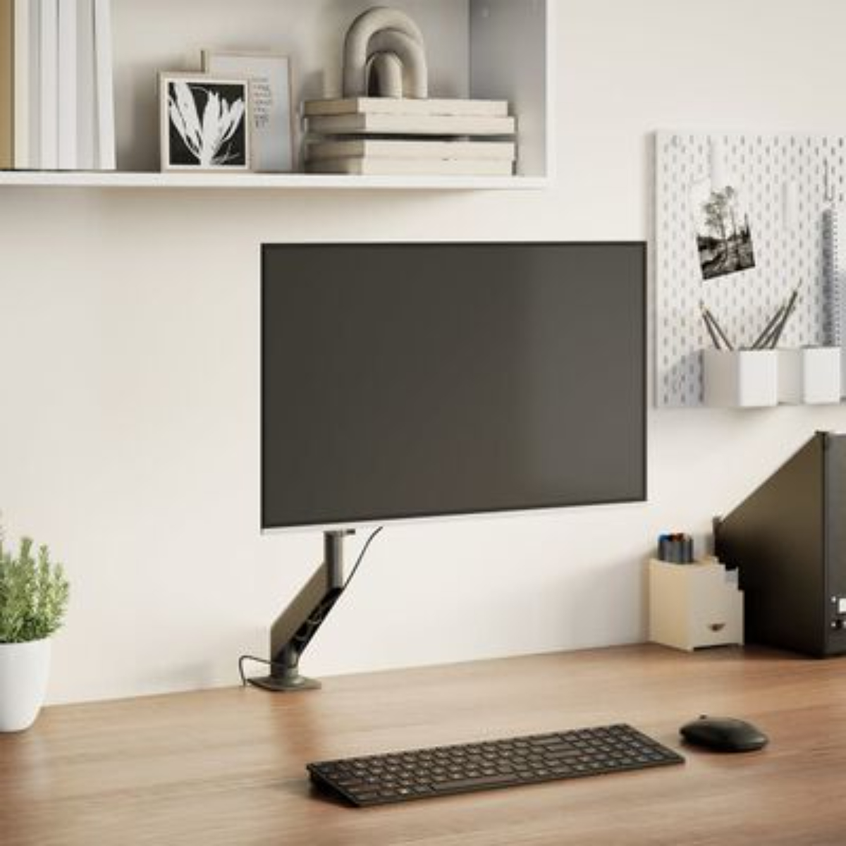 Ein Computermonitor auf einem Schreibtisch. Eine Tastatur und Maus sind davor, ein Regal mit Gegenständen darüber.