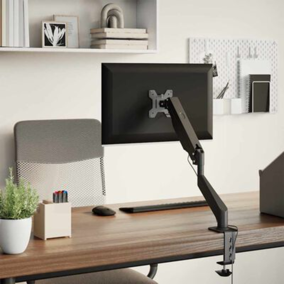 Schreibtisch-Setup mit Monitor, Monitorarm und Zubehör auf einem Holzschreibtisch.