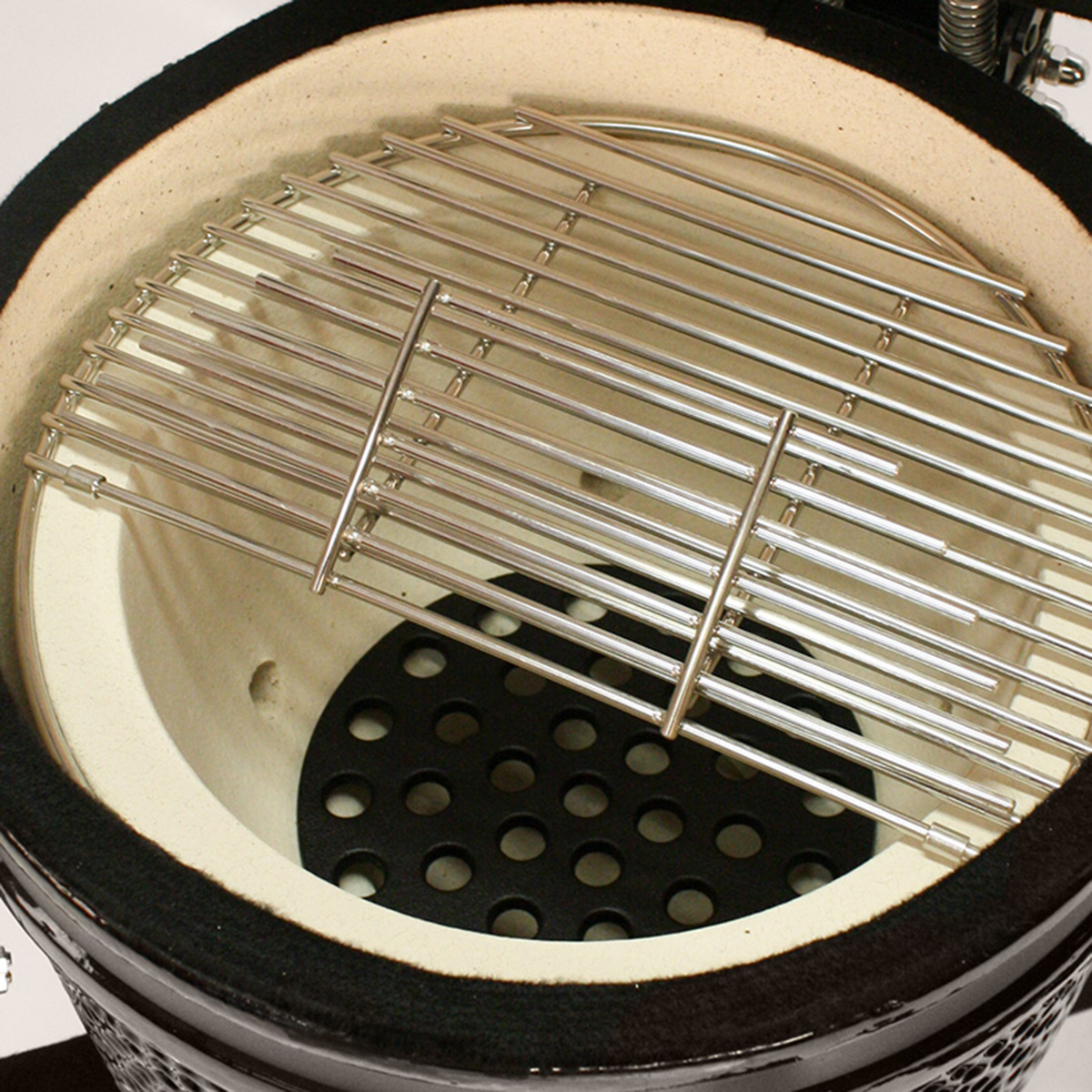 Inside of a ceramic grill with a metal grate and a black ceramic base.