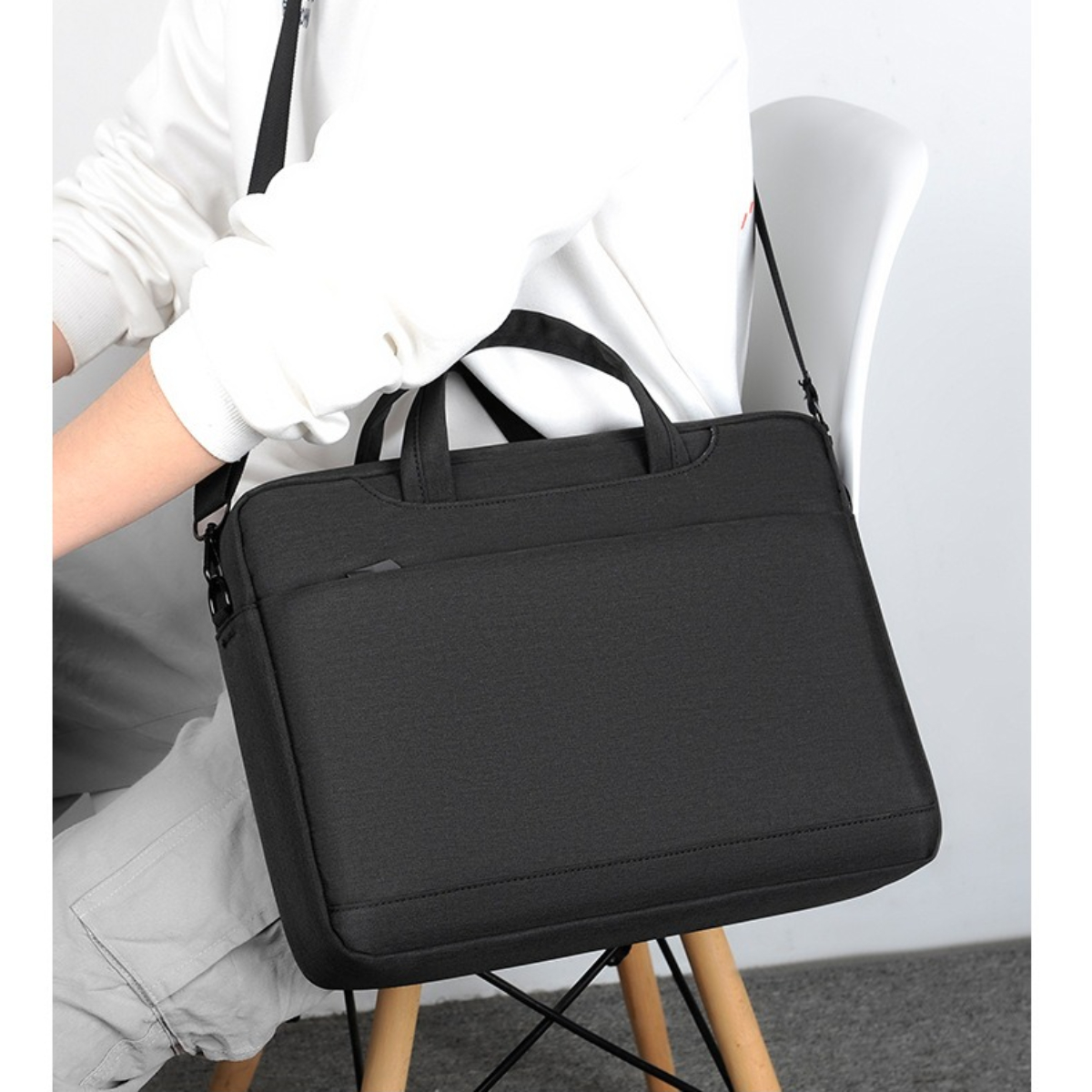 Ein Mann, der ein weißes Hemd trägt und eine schwarze Laptoptasche über der Schulter trägt.
