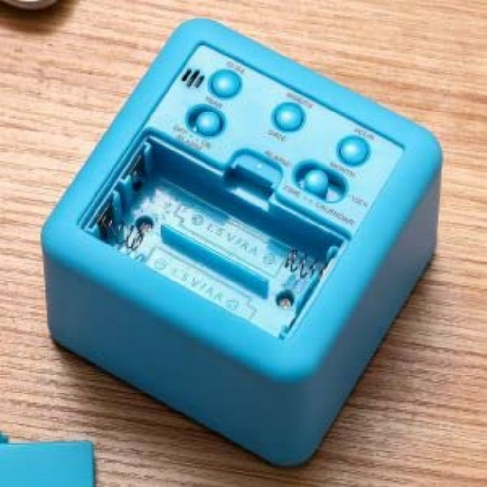 Blauer Wecker mit Knöpfen. Die Rückseite der Uhr ist geöffnet und zeigt das Batteriefach.