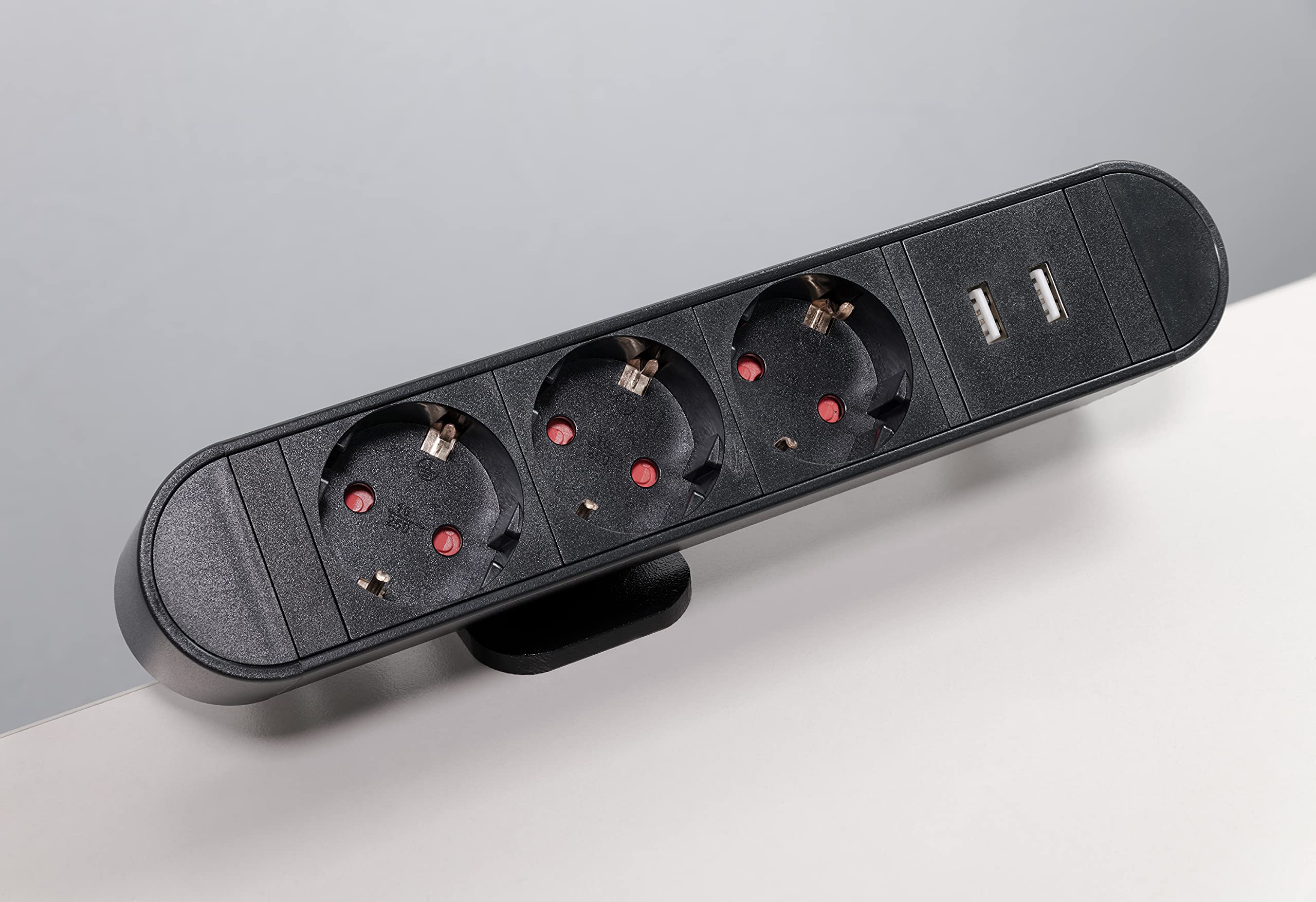 Schwarze Steckdosenleiste mit drei Steckdosen und zwei USB-Anschlüssen auf weißer Oberfläche.