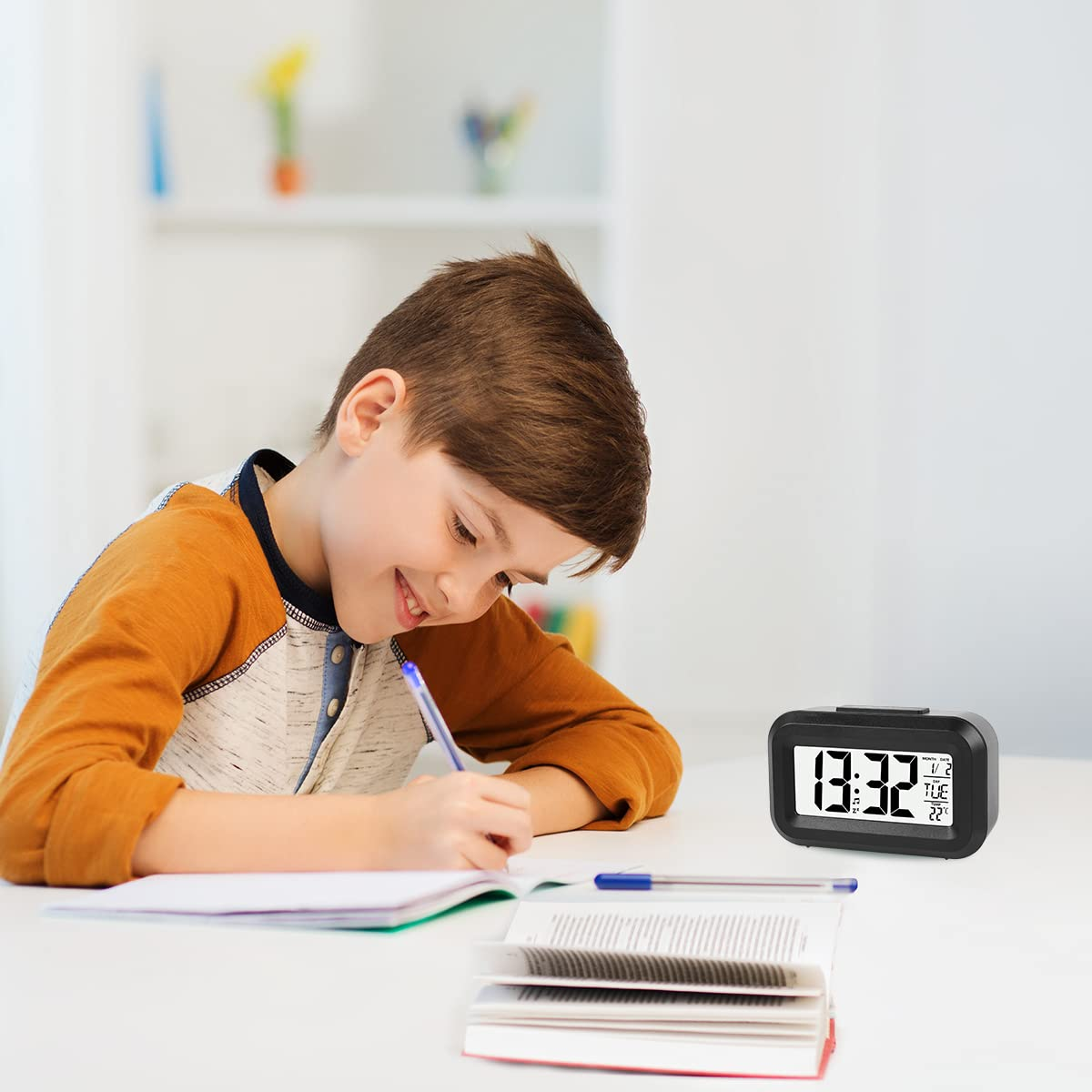 Junge schreibt an einem Schreibtisch mit Digitaluhr und offenem Buch.