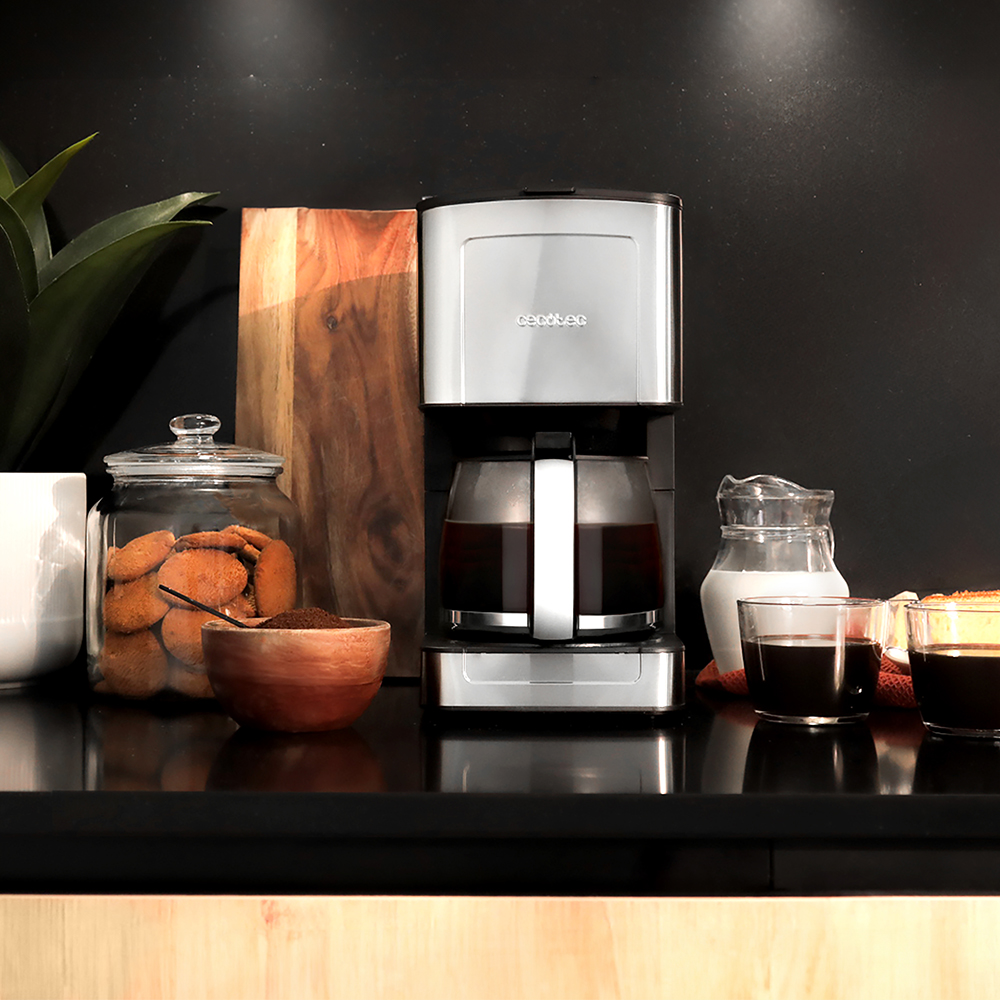 Macchina da caffè con una caraffa di vetro di caffè. Ci sono biscotti, una ciotola di legno e una brocca.