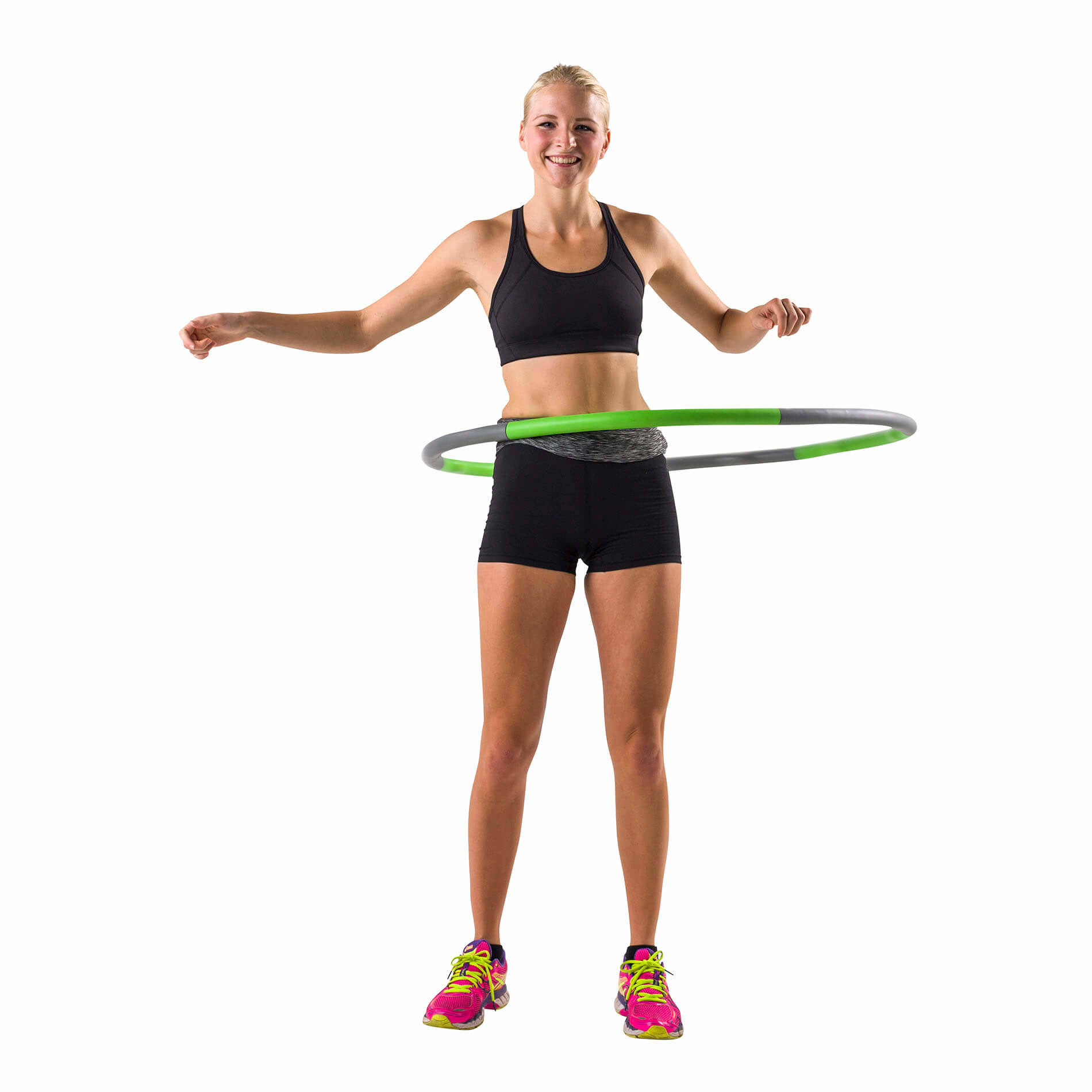 Femme en tenue de sport faisant du hula hoop, souriante. Hula hoop vert et gris. Fond blanc.