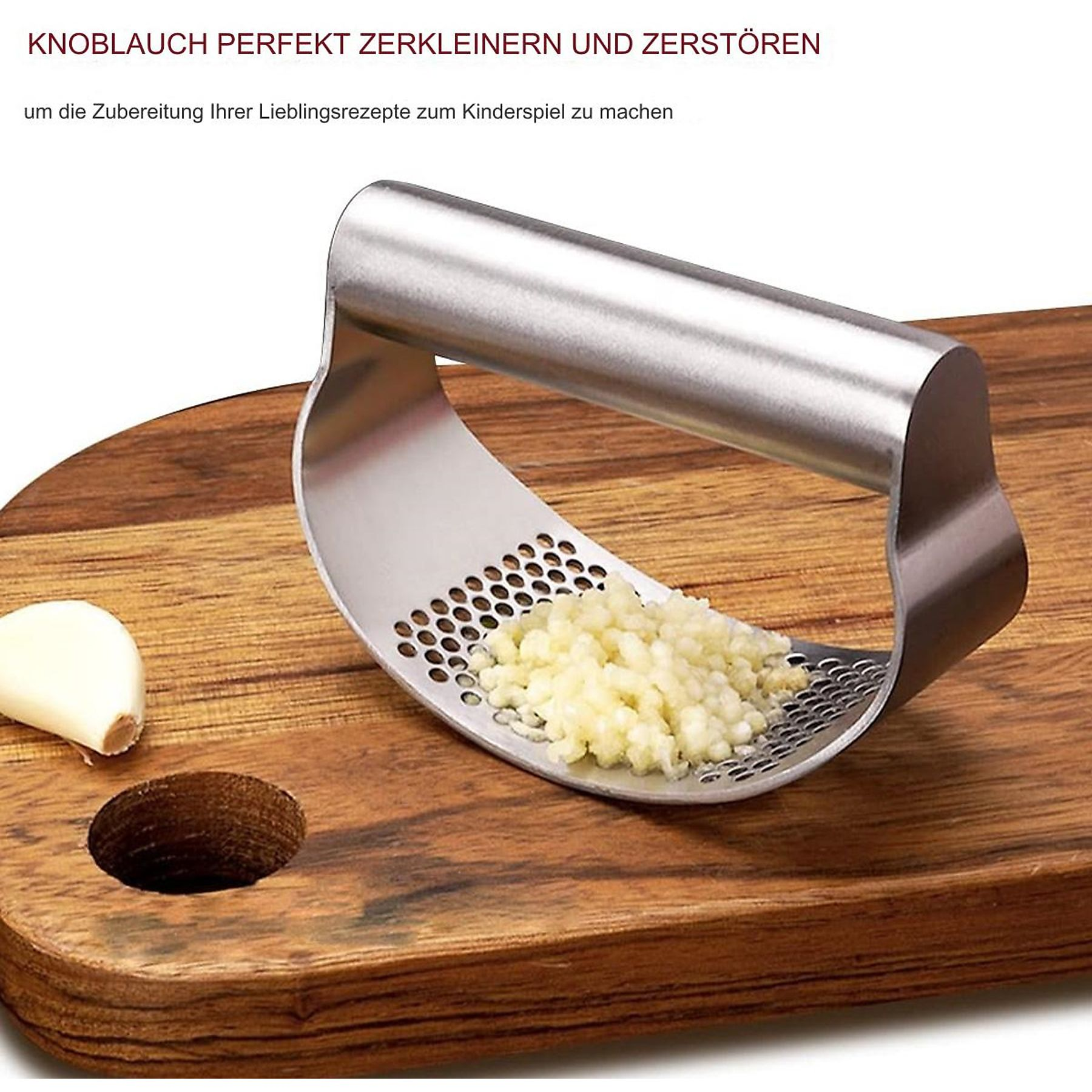 Knoblauchpresse mit gehacktem Knoblauch auf einem Holzbrett neben einer Knoblauchzehe.