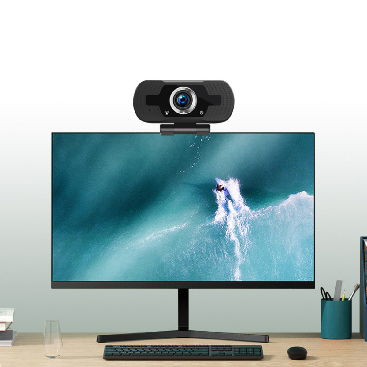 Webcam auf einem Monitor, der einen Surfer auf einer Welle zeigt, auf einem Holzschreibtisch.