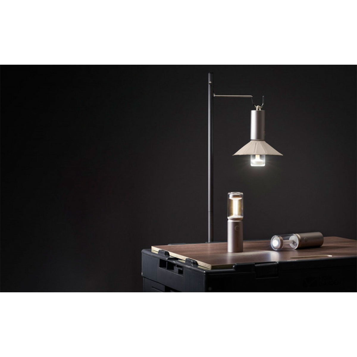 Zwei silberne Lampen, eine hohe und eine kurze, auf einem Tisch, mit schwarzem Hintergrund.