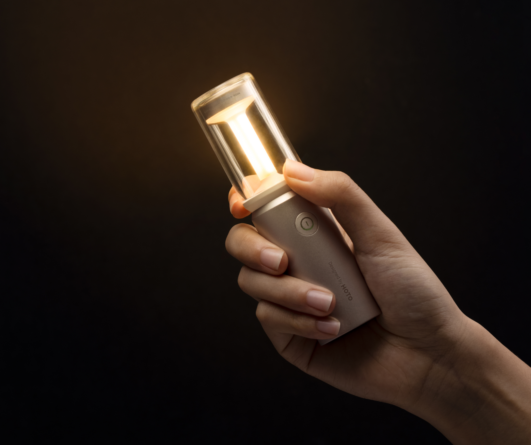 Hand, die eine zylindrische Lampe hält, die leuchtet, mit Licht auf dunklem Hintergrund.