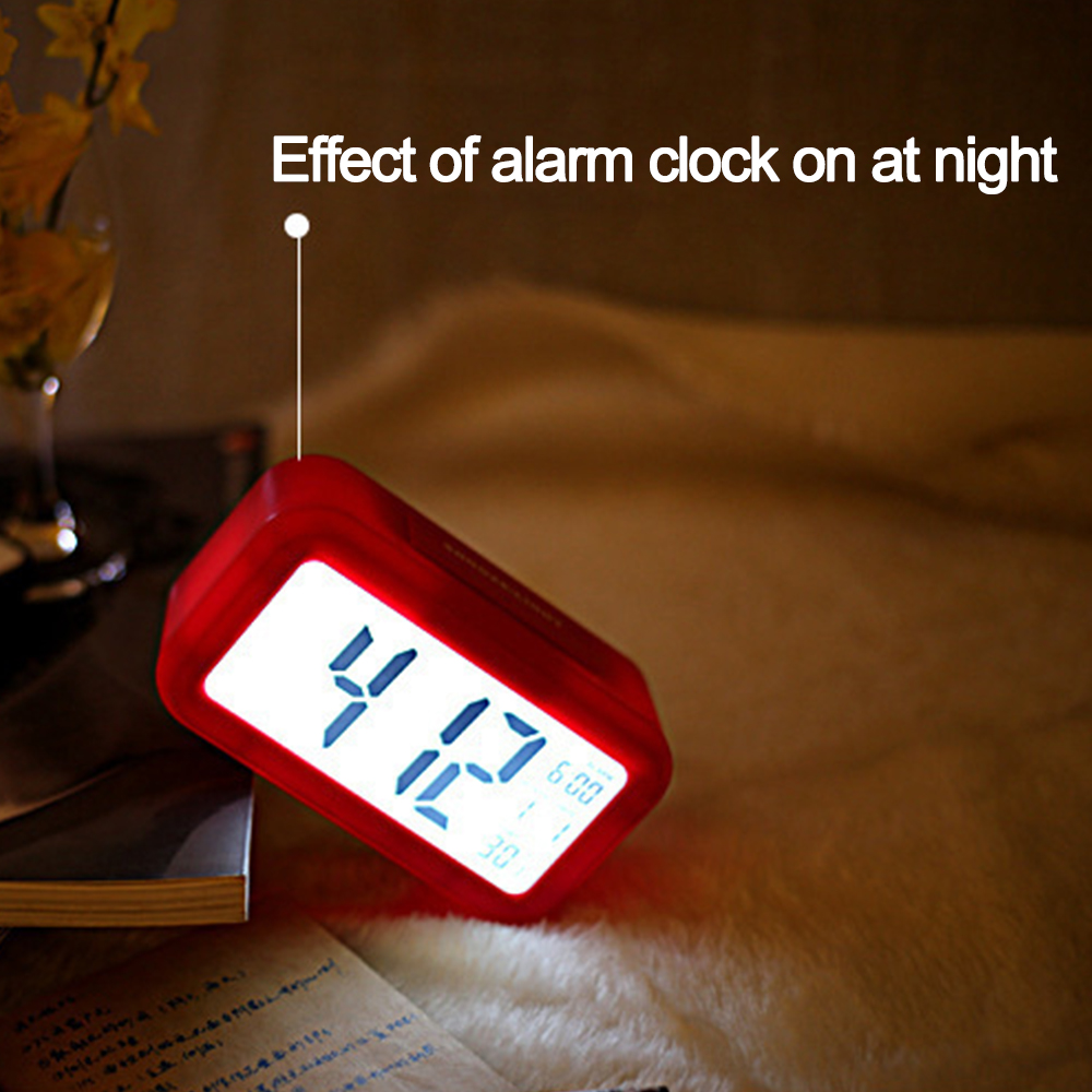 Roter digitaler Wecker auf einem Tisch. Das Display zeigt 4:12 und 6:00 Uhr an. Text: Effekt der Wecker bei Nacht.