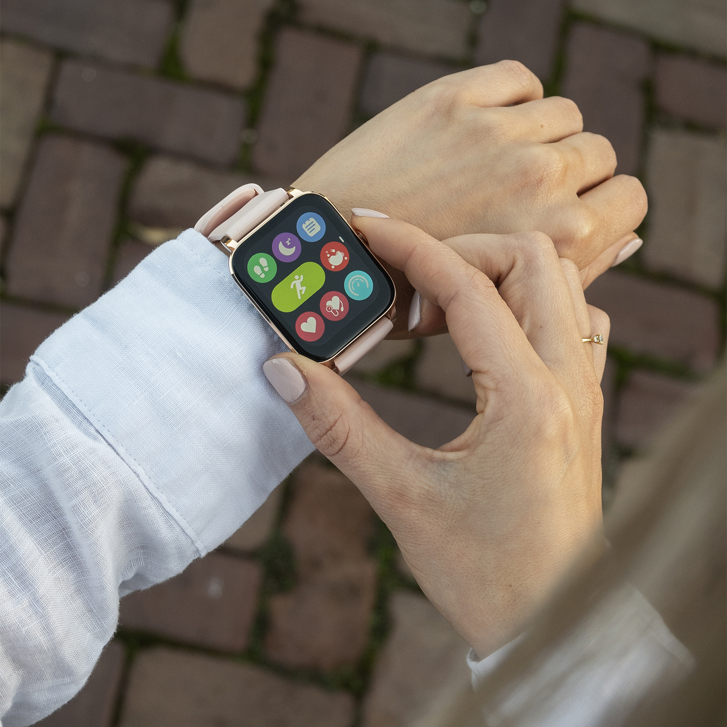 De pols van een vrouw met een smartwatch die kleurrijke pictogrammen op het scherm toont.