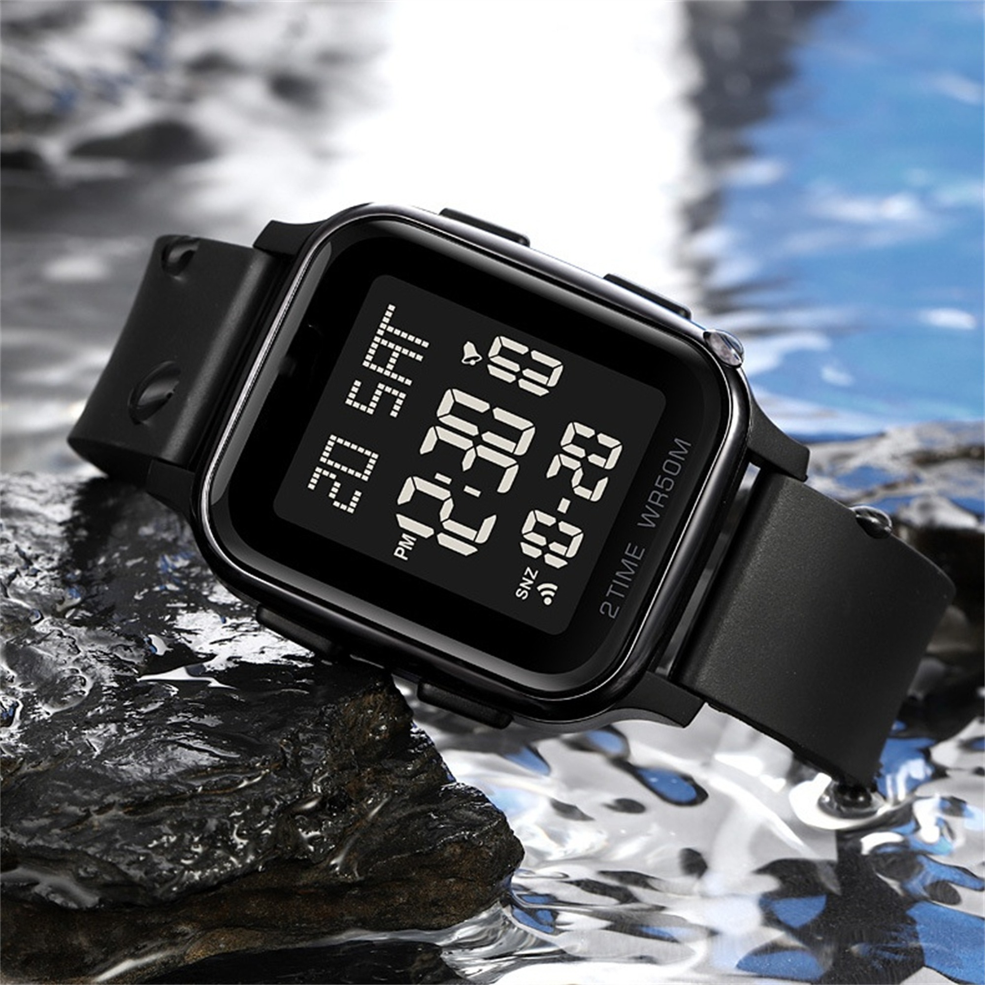 Schwarze Digitaluhr auf blauem, wässrigem Hintergrund. Der Bildschirm zeigt Zeit und Infos.