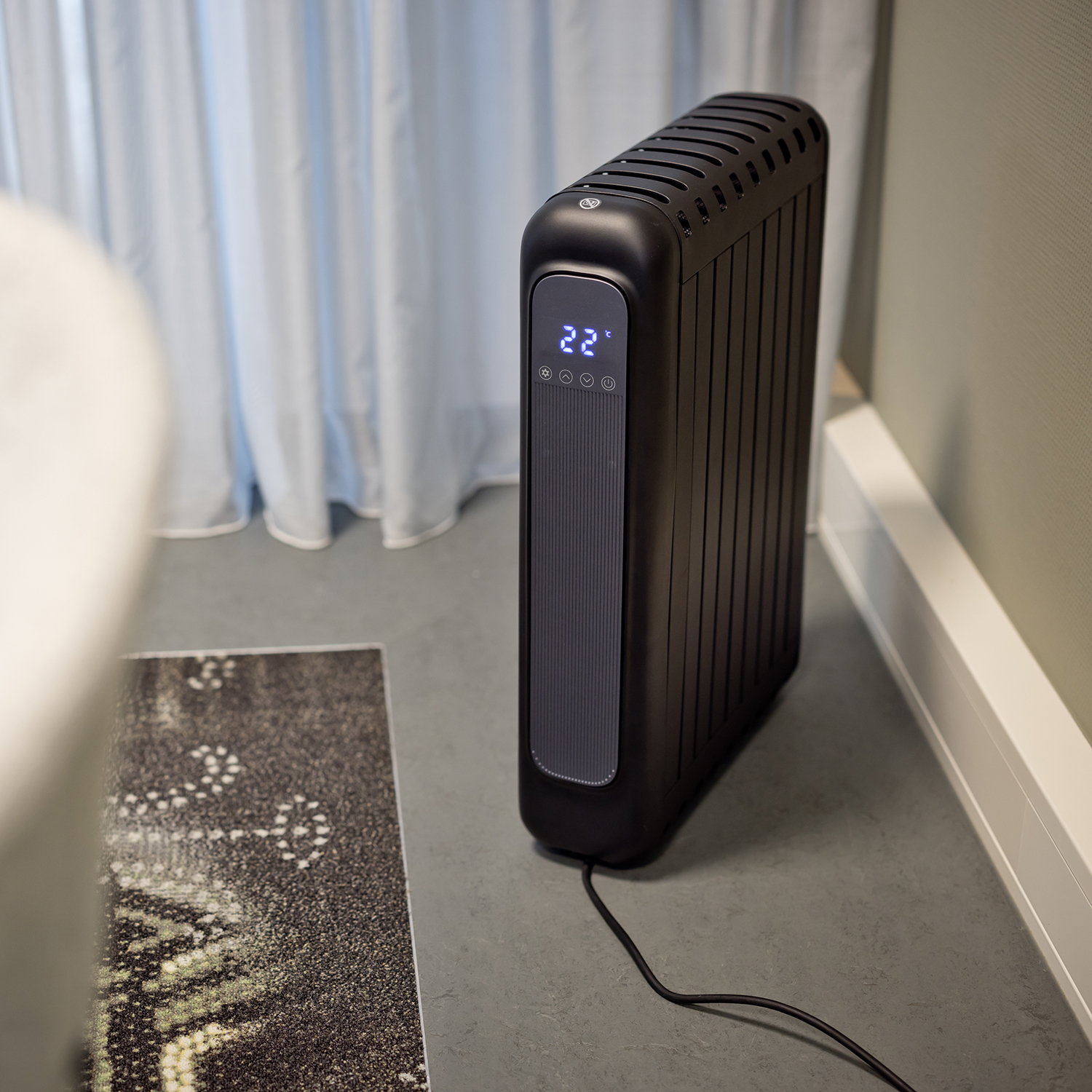 Black electric radiator with digital display. Display shows 22 degrees.