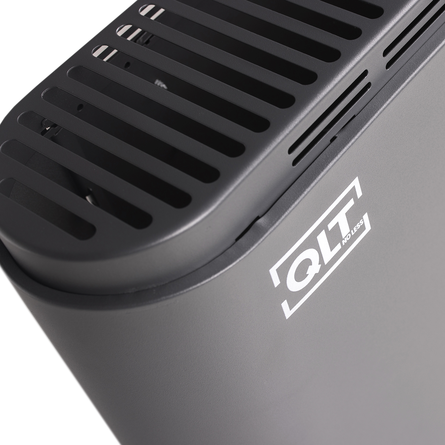 Close-up van een grijs, gebogen apparaat met een zwart rooster en het witte 'QTL NO LESS' logo.