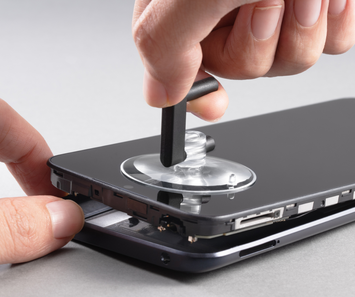 Eine Hand, die einen Saugnapf verwendet, um einen schwarzen Smartphone-Bildschirm anzuheben.