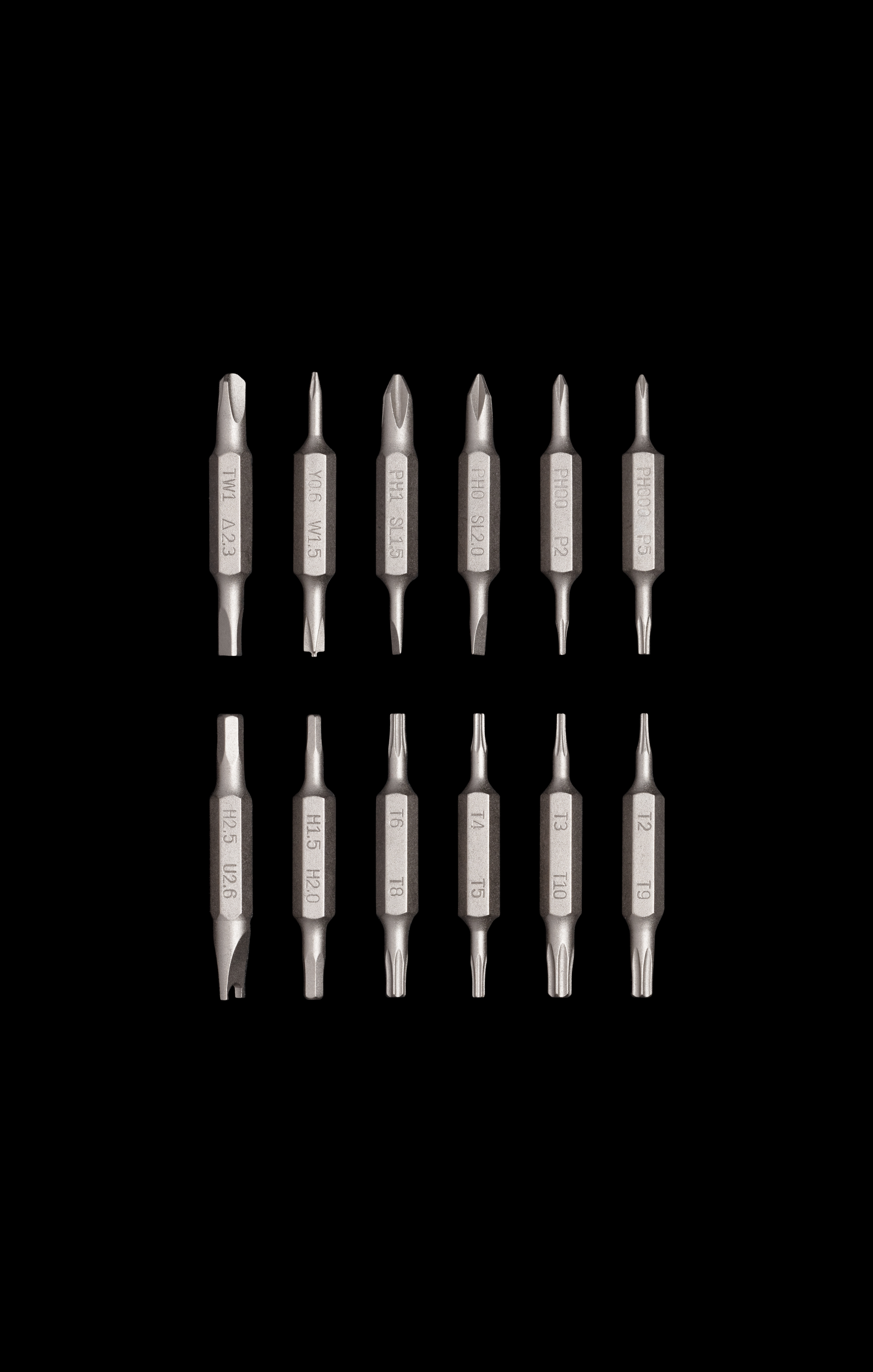 Zwölf Schraubendreher-Bits in verschiedenen Größen, angeordnet in zwei Reihen auf schwarzem Untergrund. Silberfarbene Bits.