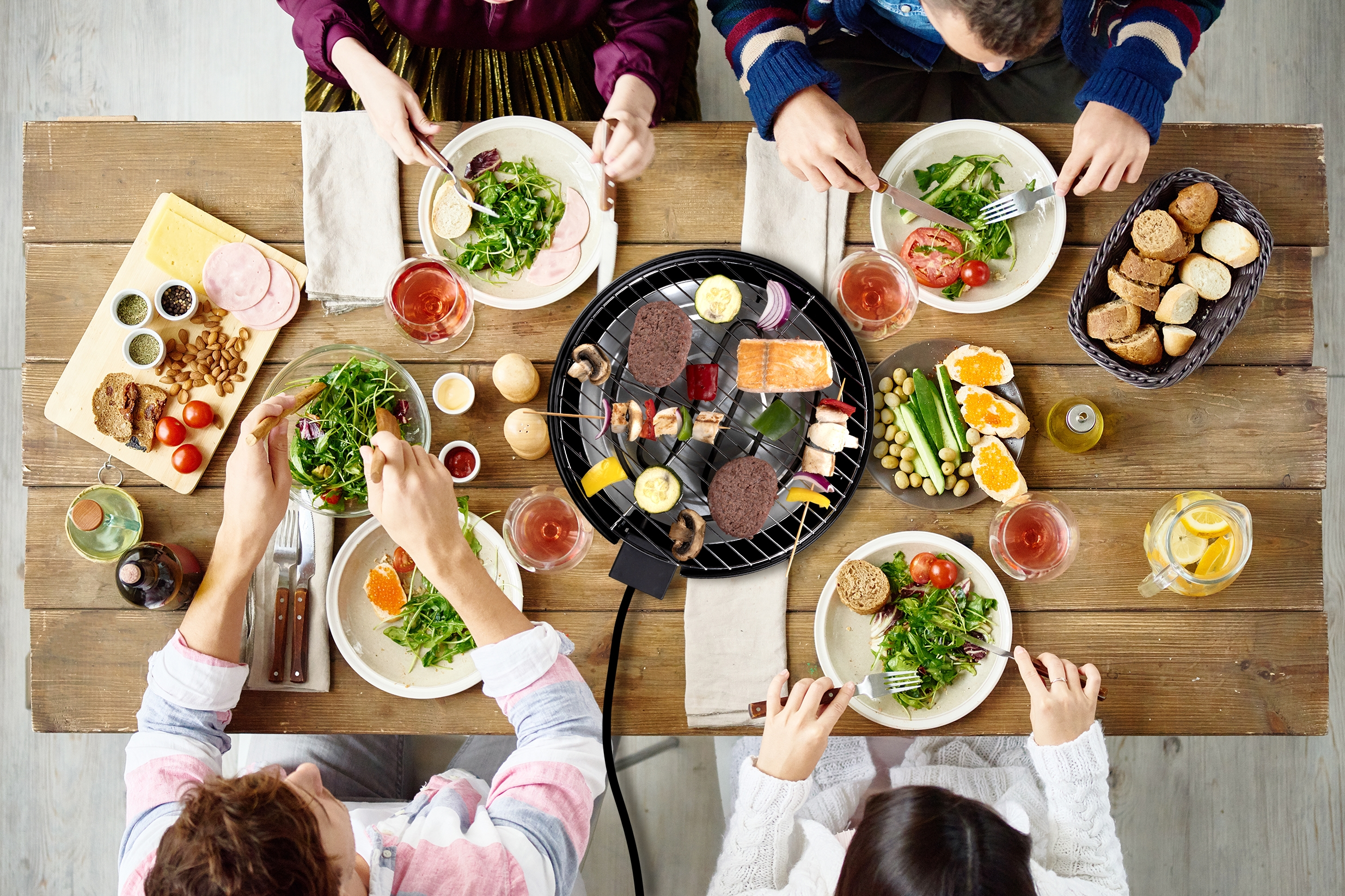 Overhead shot of people eating around a table with a grill in the center.