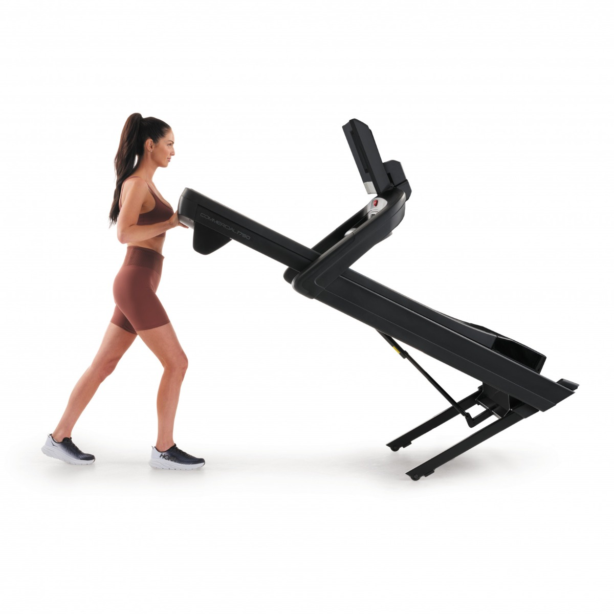 Woman tilting up a black treadmill.