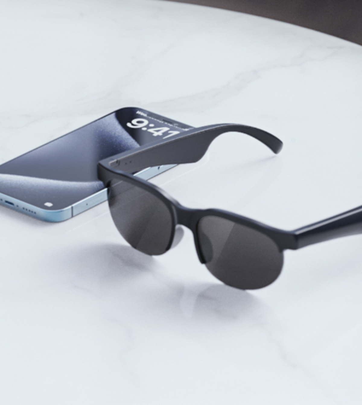 Sonnenbrille neben einem Telefon, das 9:41 auf einer Marmoroberfläche zeigt.