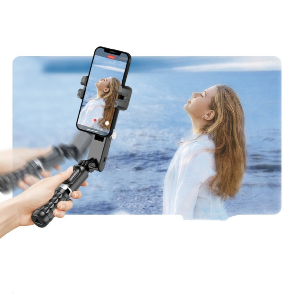 Eine Frau filmt sich mit einem Selfie-Stick in der Nähe des Ozeans. Das Telefon ist sichtbar.