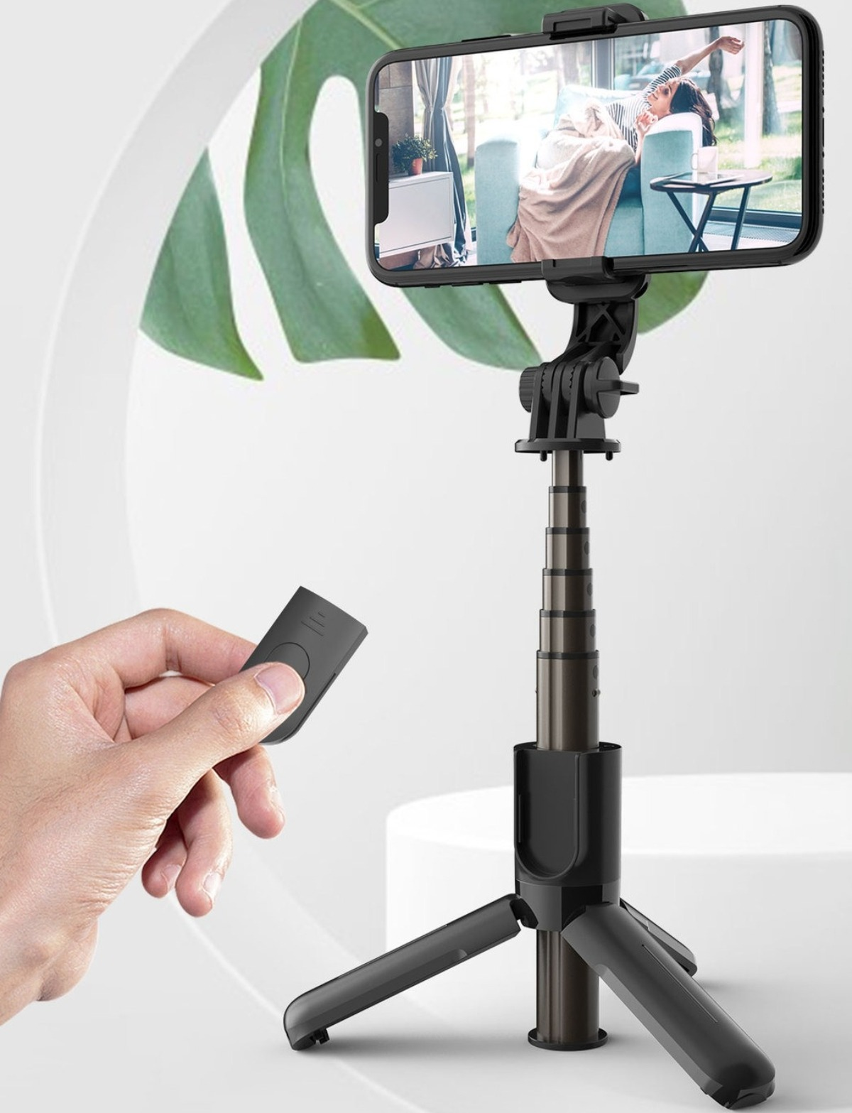 Ein Smartphone an einem Stativ befestigt, mit Fernbedienung in der Hand.