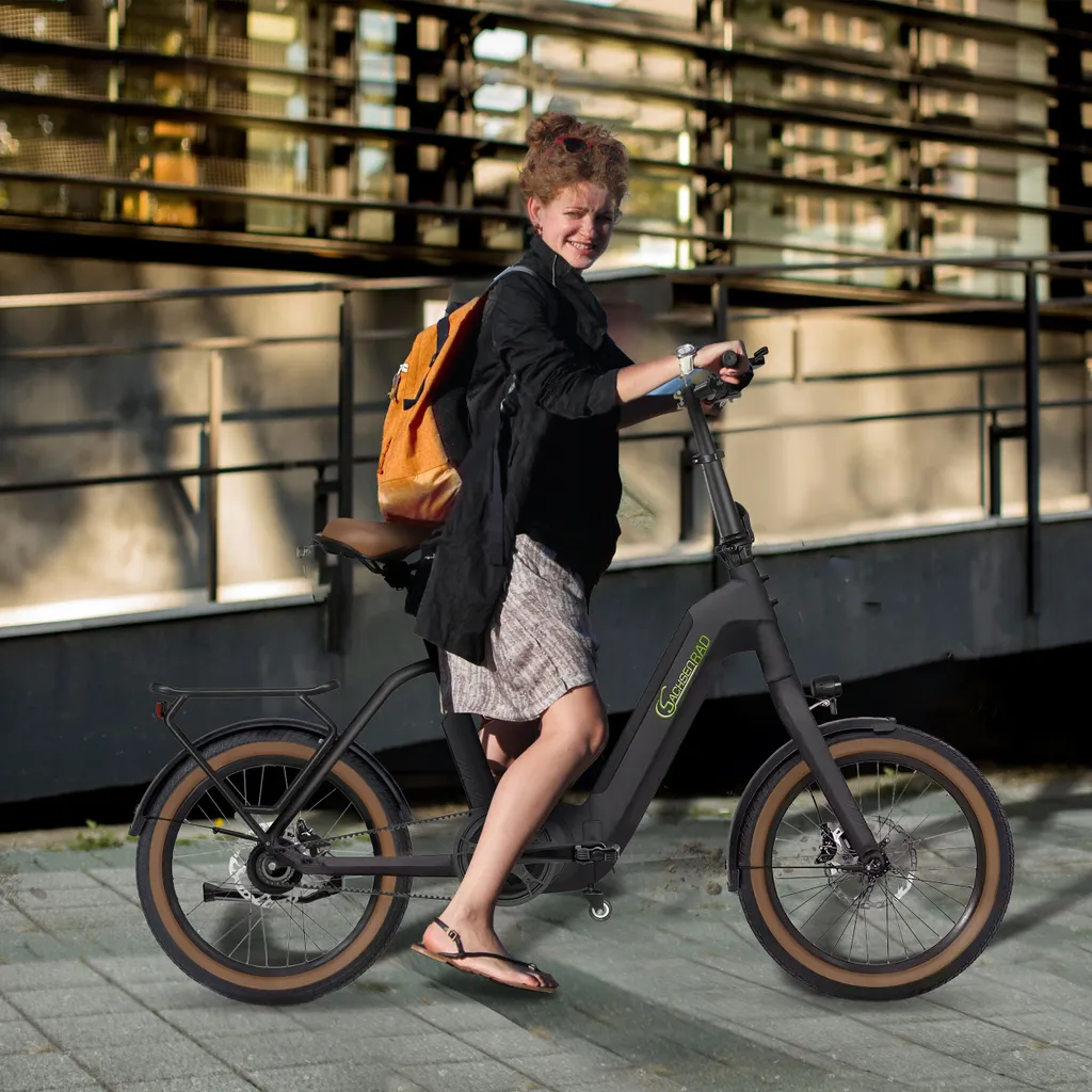 Ein Mädchen fährt auf einer schwarzen E-Bike auf einer Stadtstraße, mit Rucksack und Shorts.