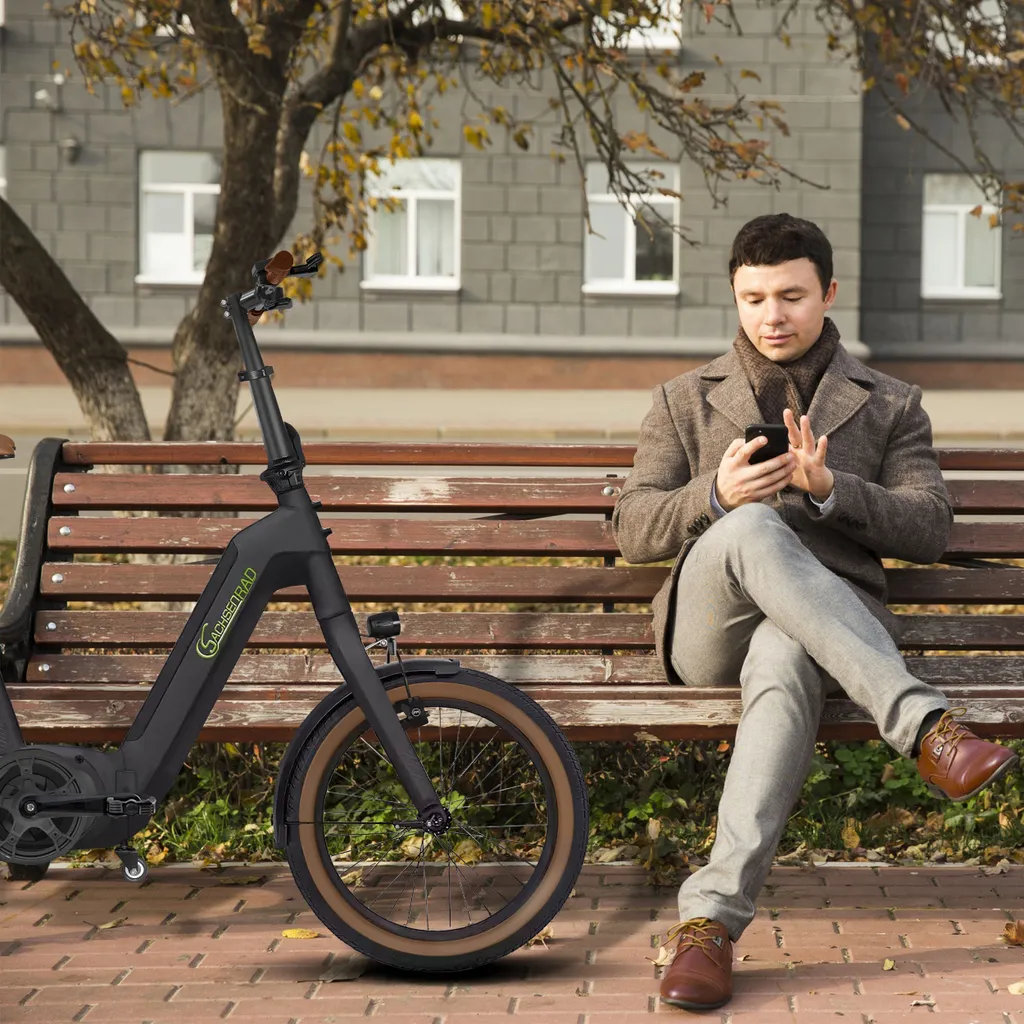 Ein Mann sitzt auf einer Bank, benutzt sein Telefon, neben ihm steht ein Fahrrad.