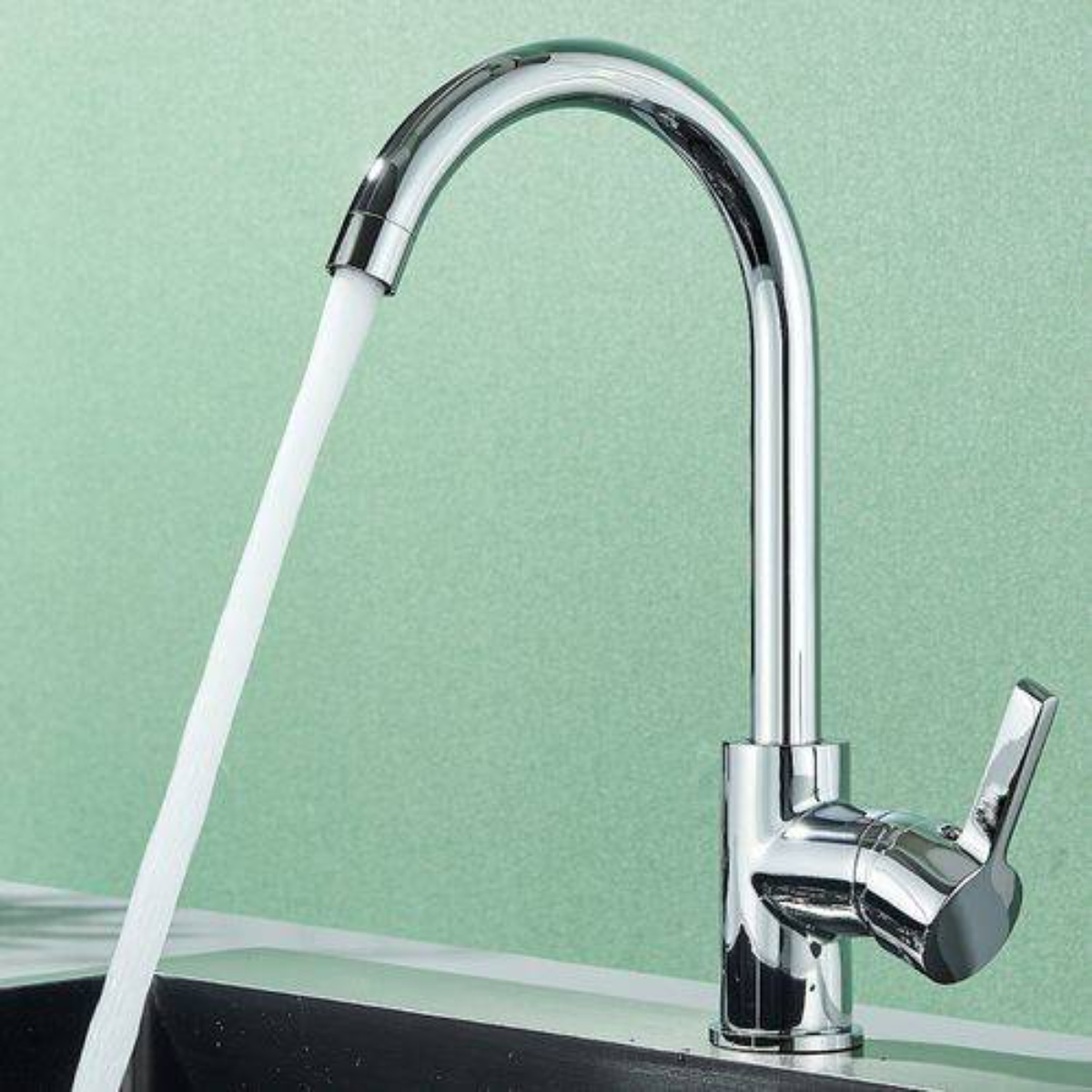 Chrom-Wasserhahn, Wasser fließt. Grüner Hintergrund. Schwarzes Waschbecken.