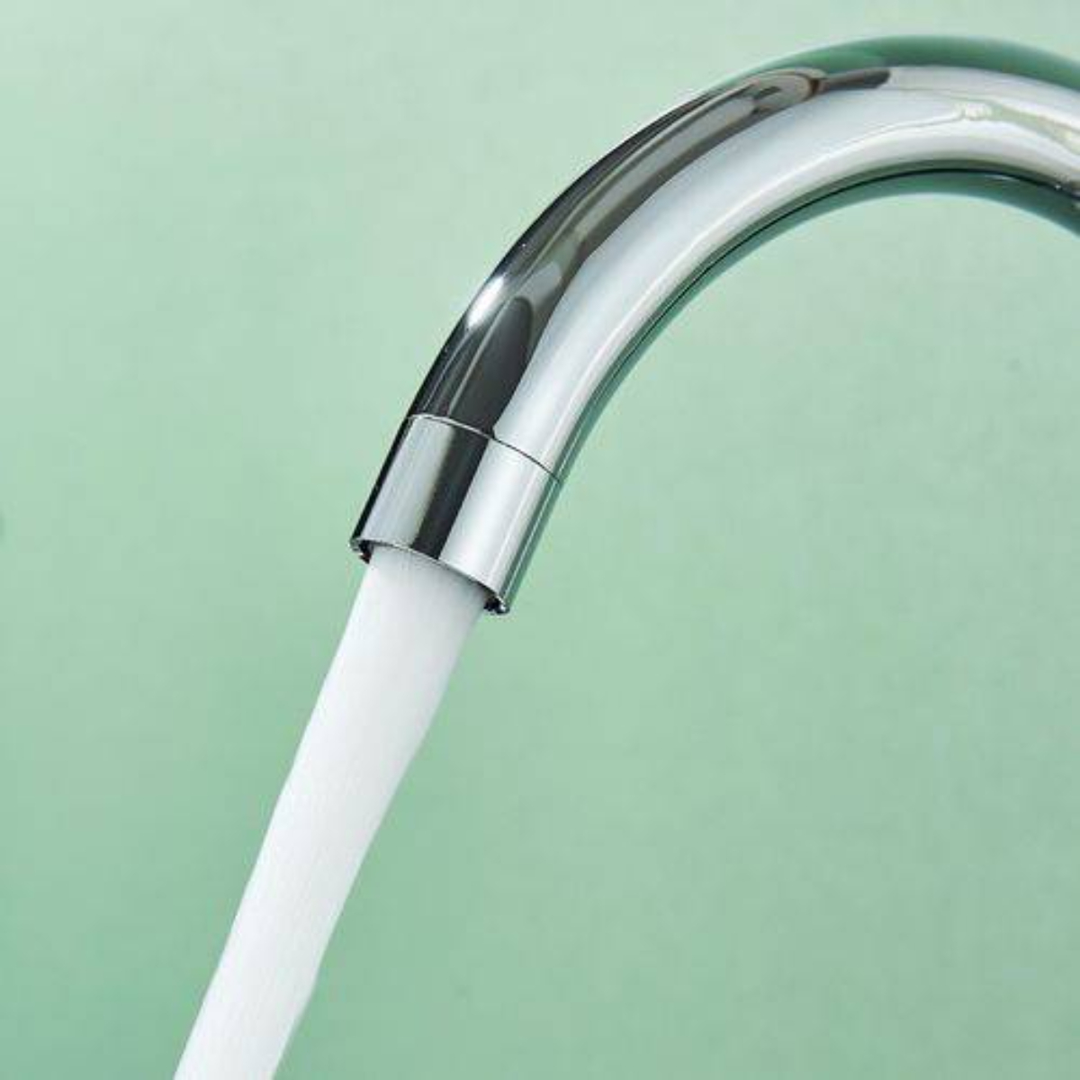 Nahaufnahme eines silbernen Wasserhahns mit einem nach unten fließenden Wasserstrahl.