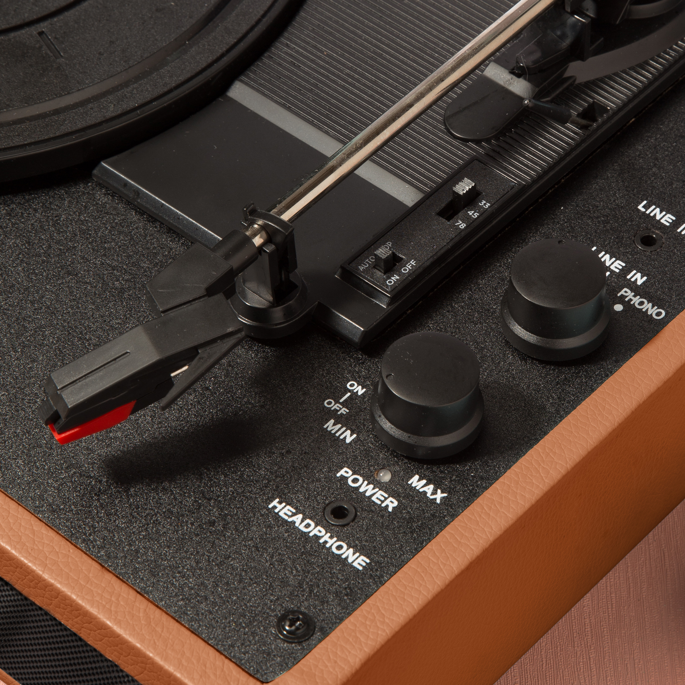 Zbliżenie na gramofon w stylu vintage z elementami sterowania: zasilanie, głośność i igła.