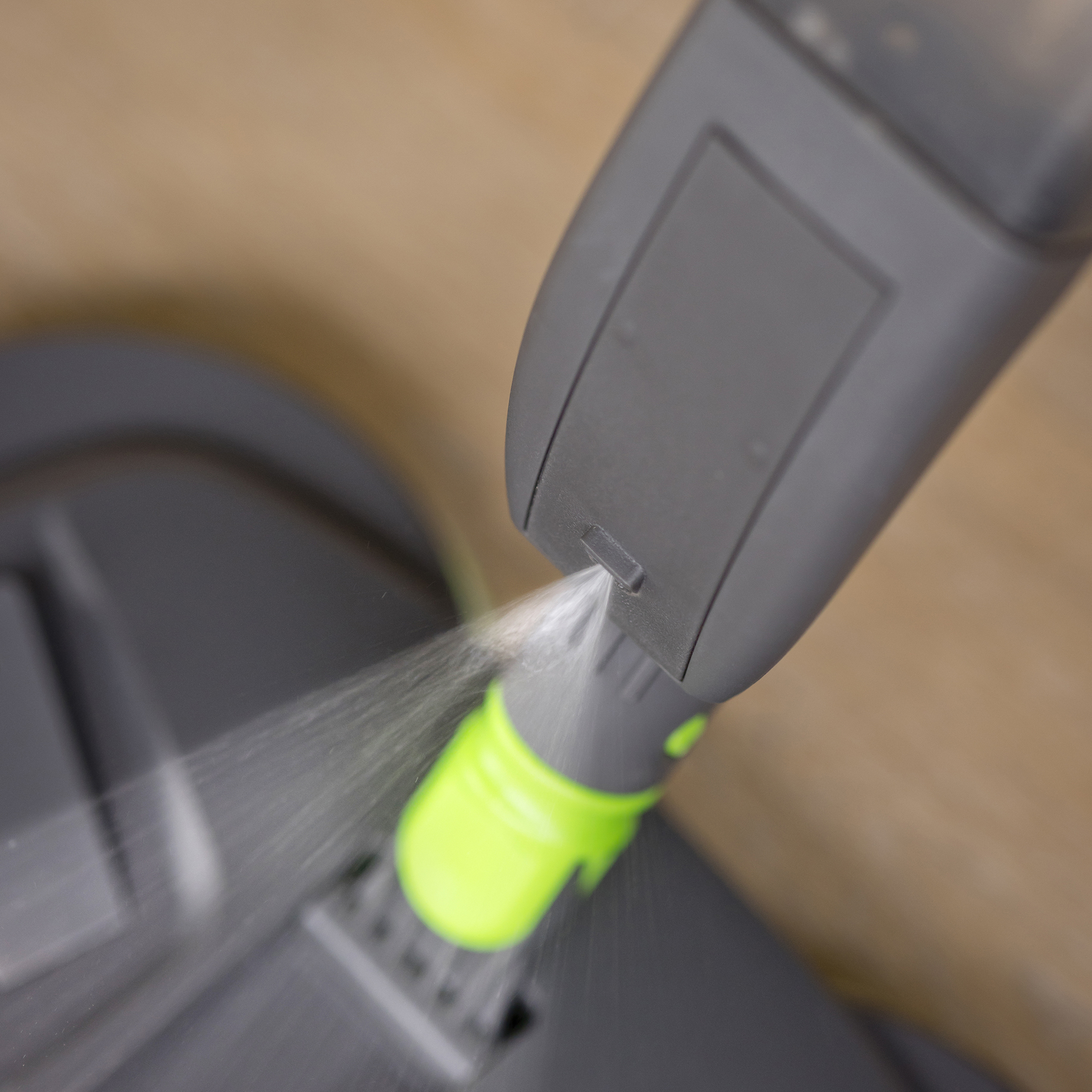 Close-up van een schoonmaaktool die water sproeit, groen en grijze kleuren.