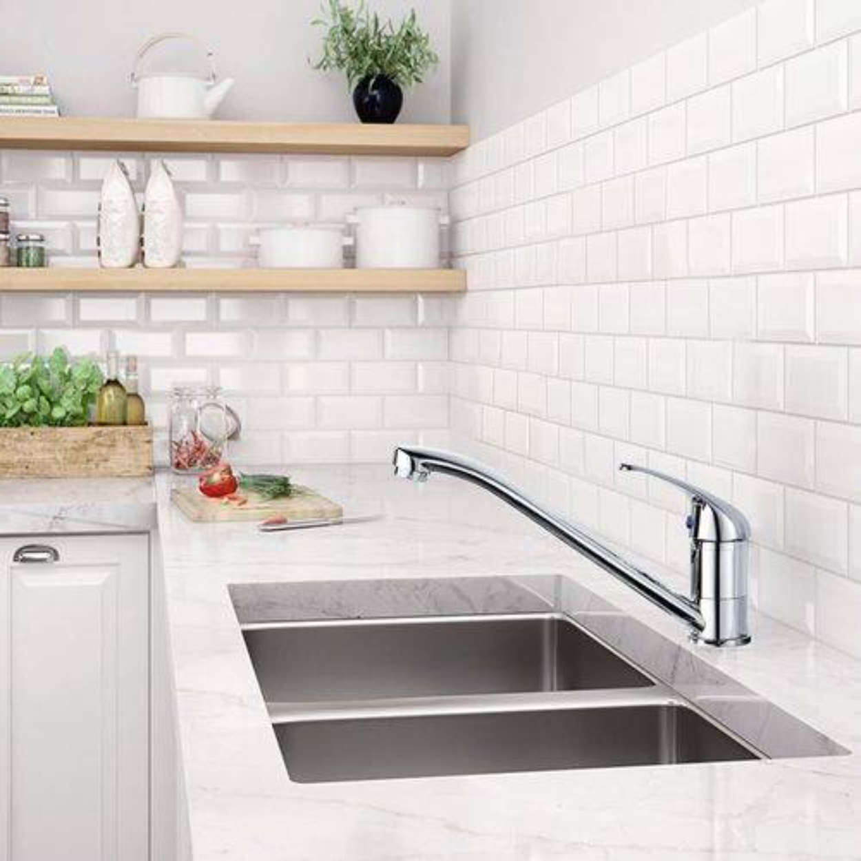 Ein Küchenspülbecken mit Chromarmatur. Weißer Fliesenspiegel. Holzregale mit Gläsern und Pflanzen.