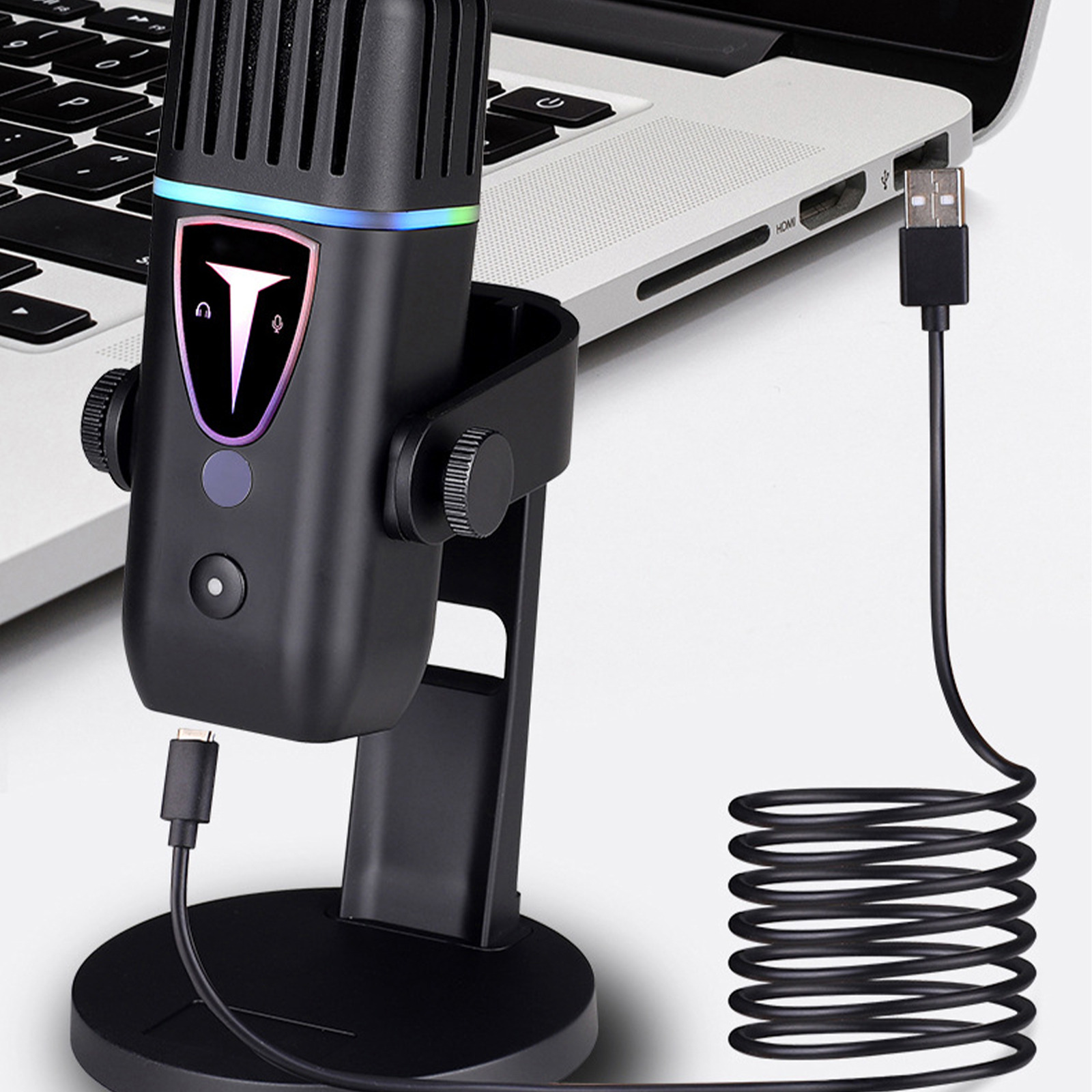 Ein schwarzes Mikrofon auf einem Ständer neben einem Laptop und einem USB-Kabel.