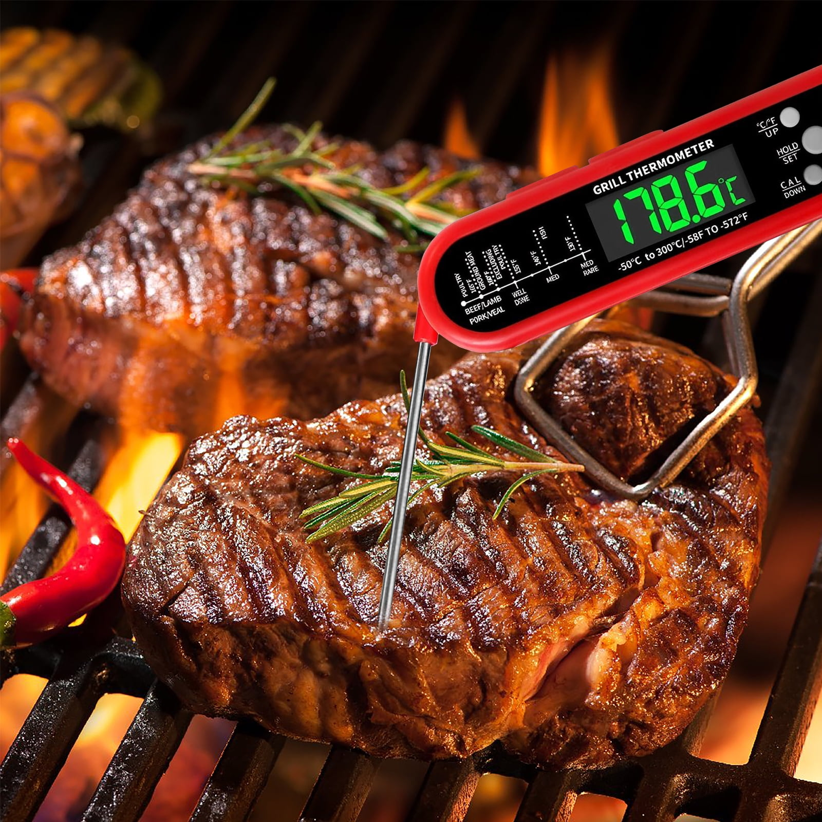 Medium-rare Steak auf einem Grill mit eingestecktem Thermometer. Rote Chili und Rosmarin-Garnitur.