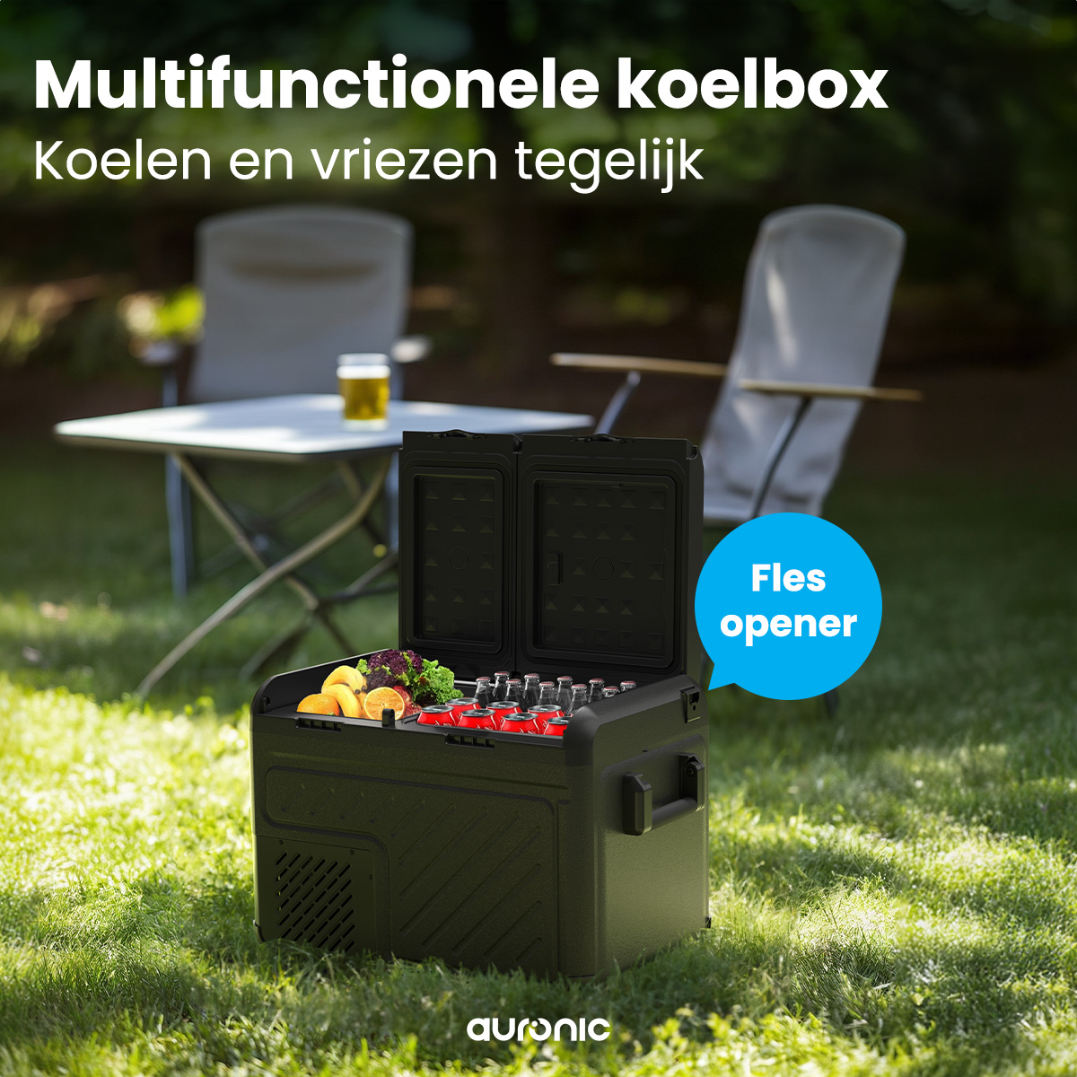 Een zwarte koeler met open deksel, drankjes en fruit op gras, met stoelen en tafel op de achtergrond.