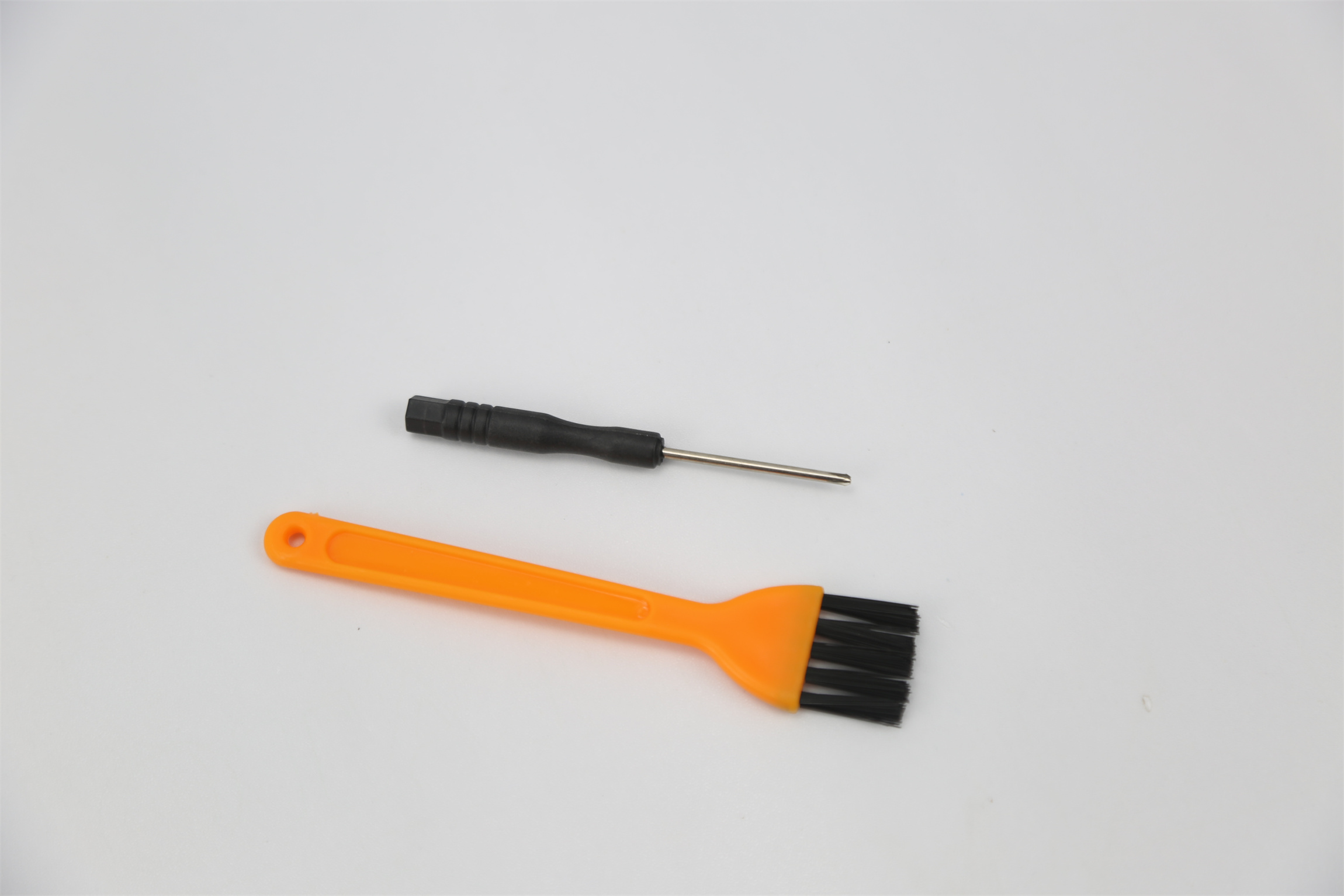 Dwa narzędzia do czyszczenia: mała szczotka i śrubokręt.