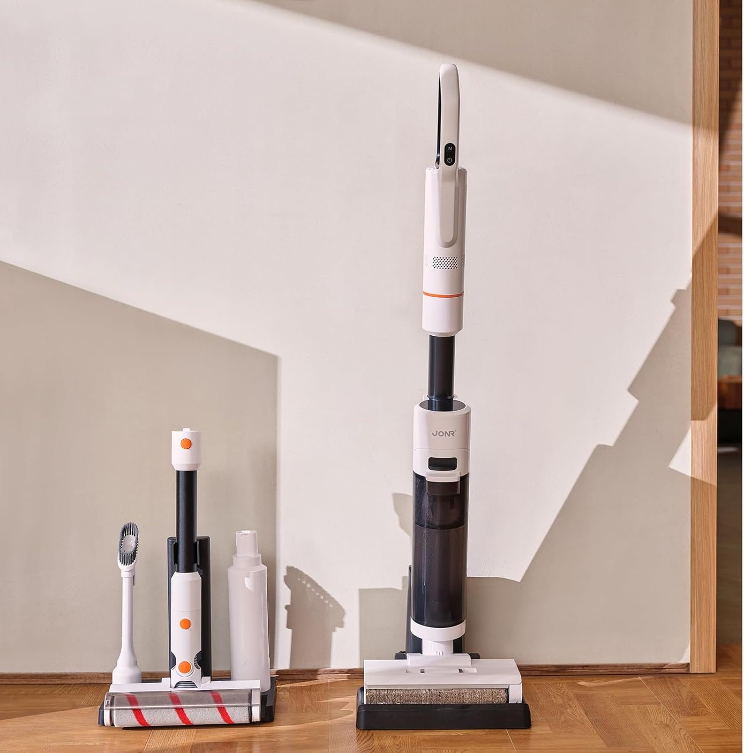 Biało-czarny bezprzewodowy odkurzacz z akcesoriami, oparty o ścianę.