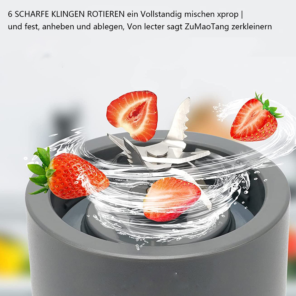 Ein Mixermesser zerkleinert Erdbeeren in Stücke, mit Wasserspritzern, auf einer grauen Mixerbasis.