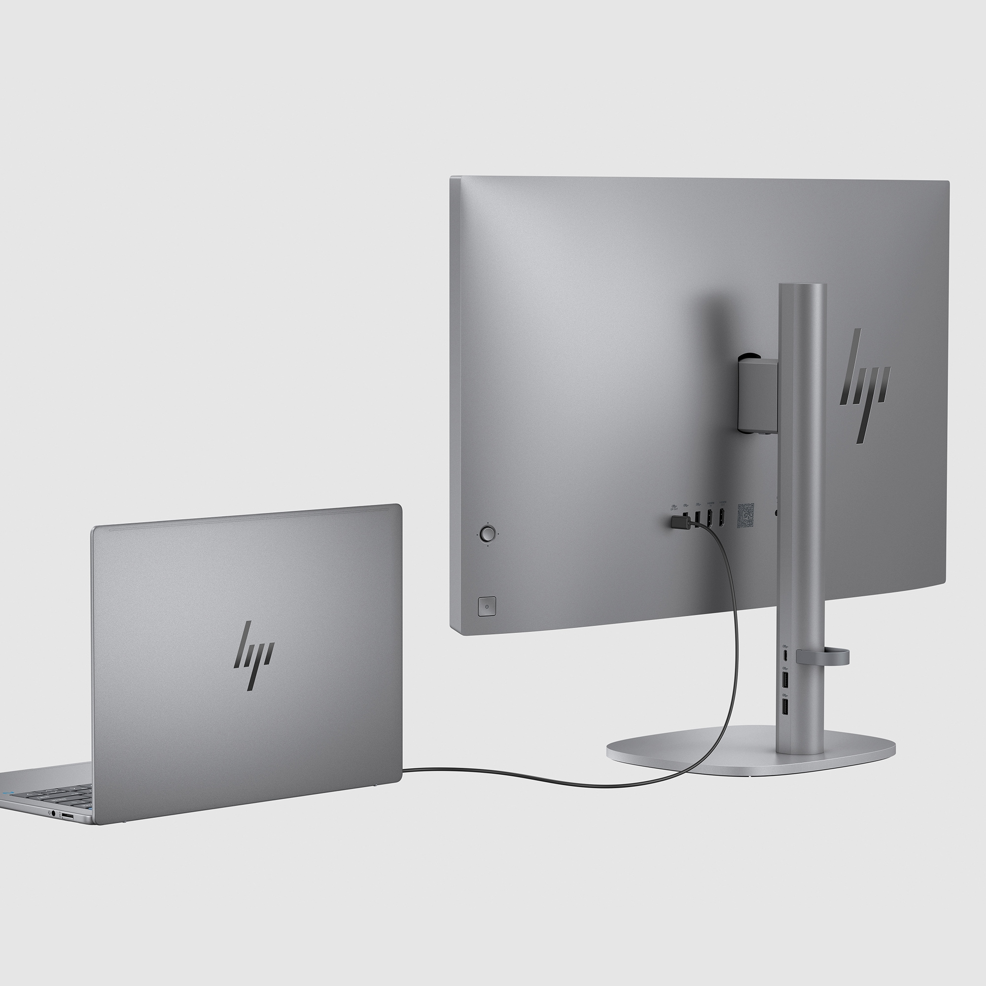 Ein silberner Laptop, der an einen silbernen All-in-One-Computer angeschlossen ist. Die Rückseite hat Anschlüsse.