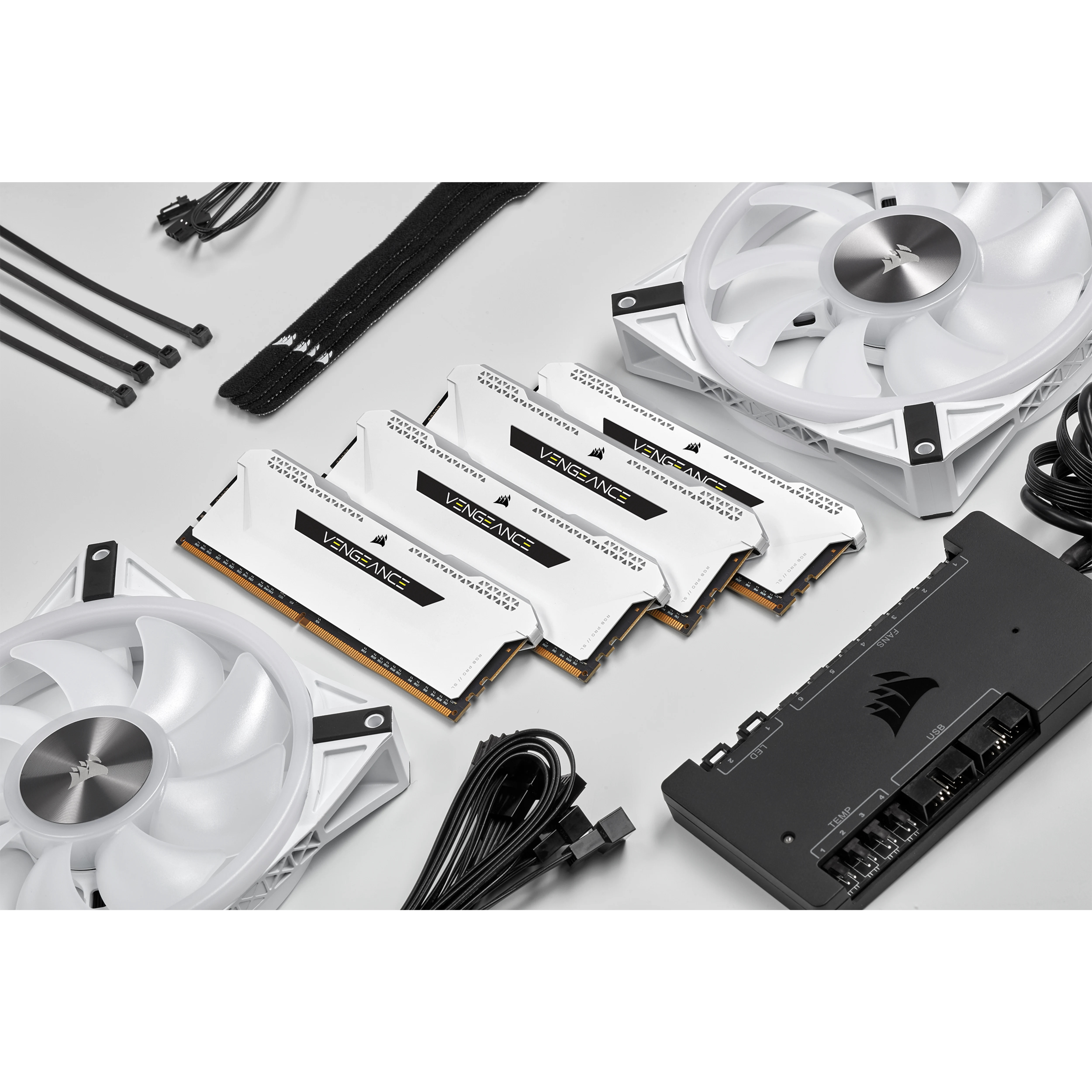 Podzespoły komputera: kości RAM, wentylatory i kontroler na białej powierzchni.