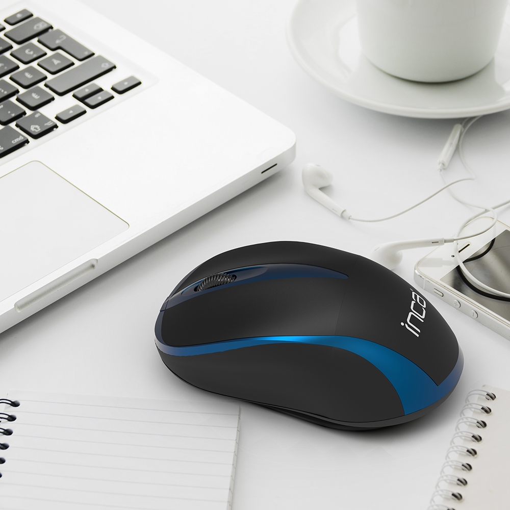 Eine schwarz-blaue kabellose Maus neben einem Laptop, Telefon und Kopfhörern auf weißer Oberfläche.